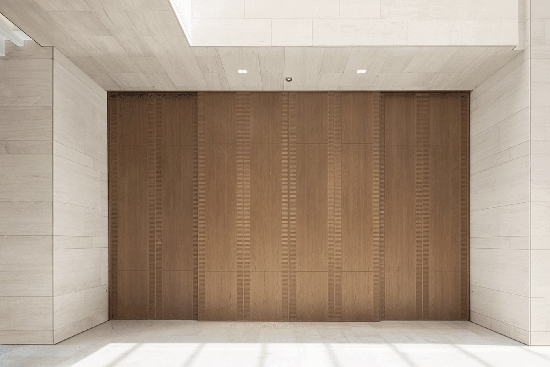 Modern lobby featuring a large wooden wall and white marble floor.