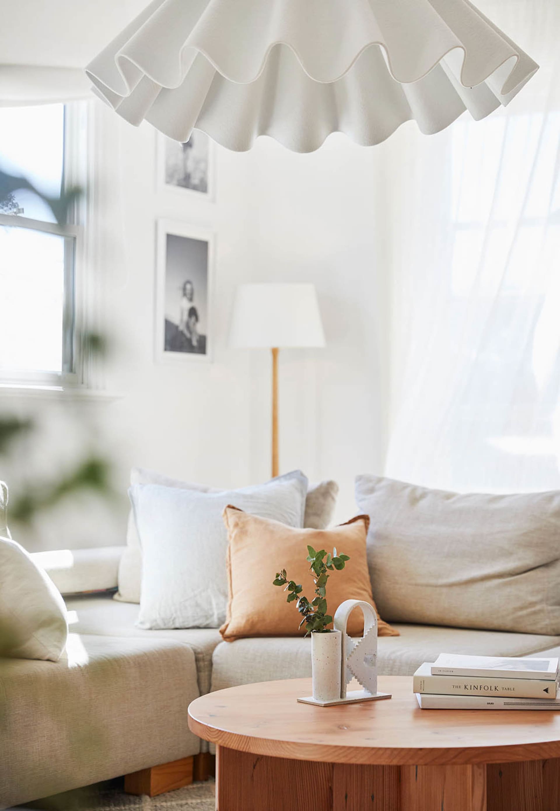 A minimalist living room featuring a light-colored fabric sofa, round wooden coffee table, and decorative elements like a fri