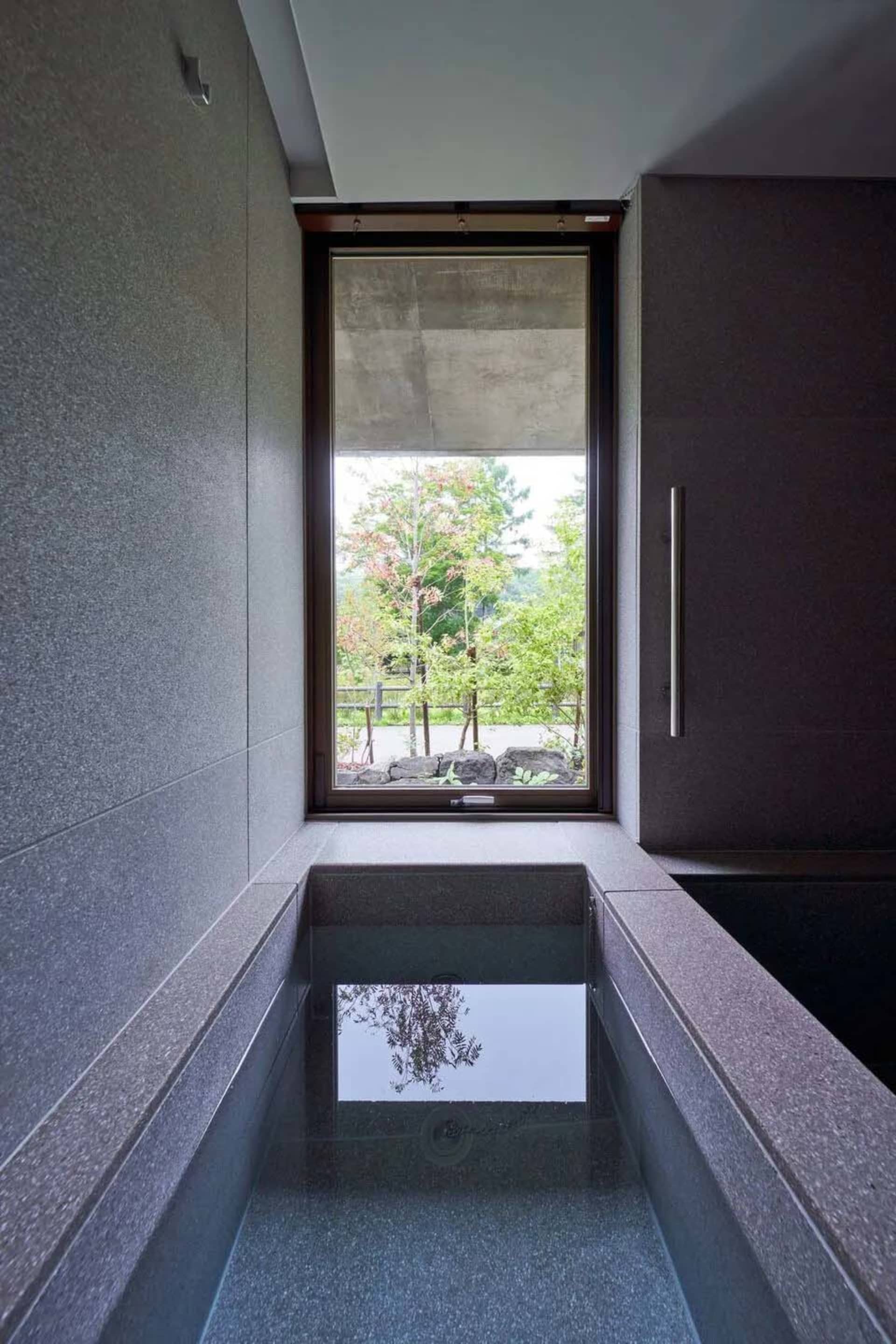 Industrial-style interior with concrete walls, a window, and a view of greenery.