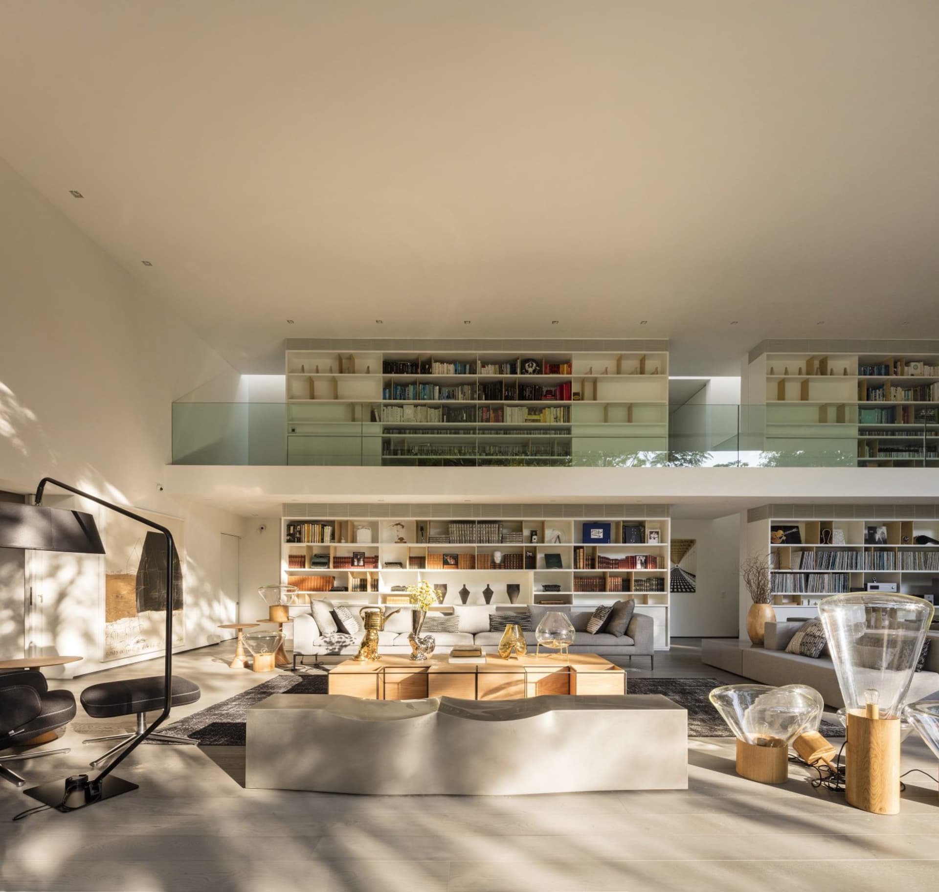 A minimalist living room with a concrete and wood coffee table, glass lamp, and wood sofa.