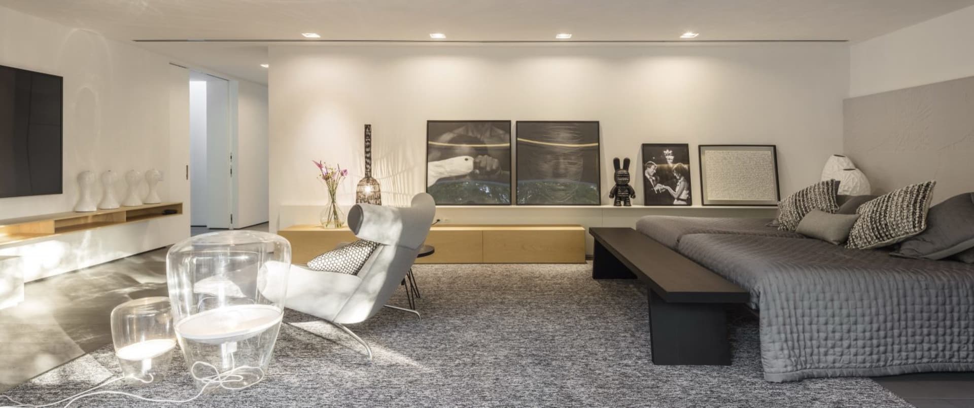 A modern minimalist living room featuring wood, glass, and fabric elements.