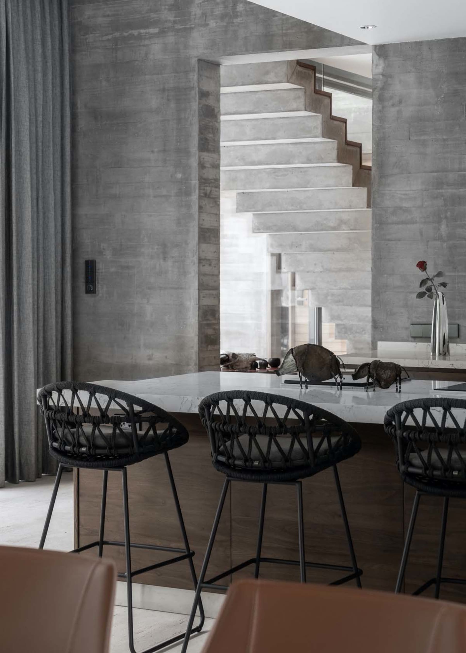 A modern kitchen with a concrete countertop and industrial-style seating.