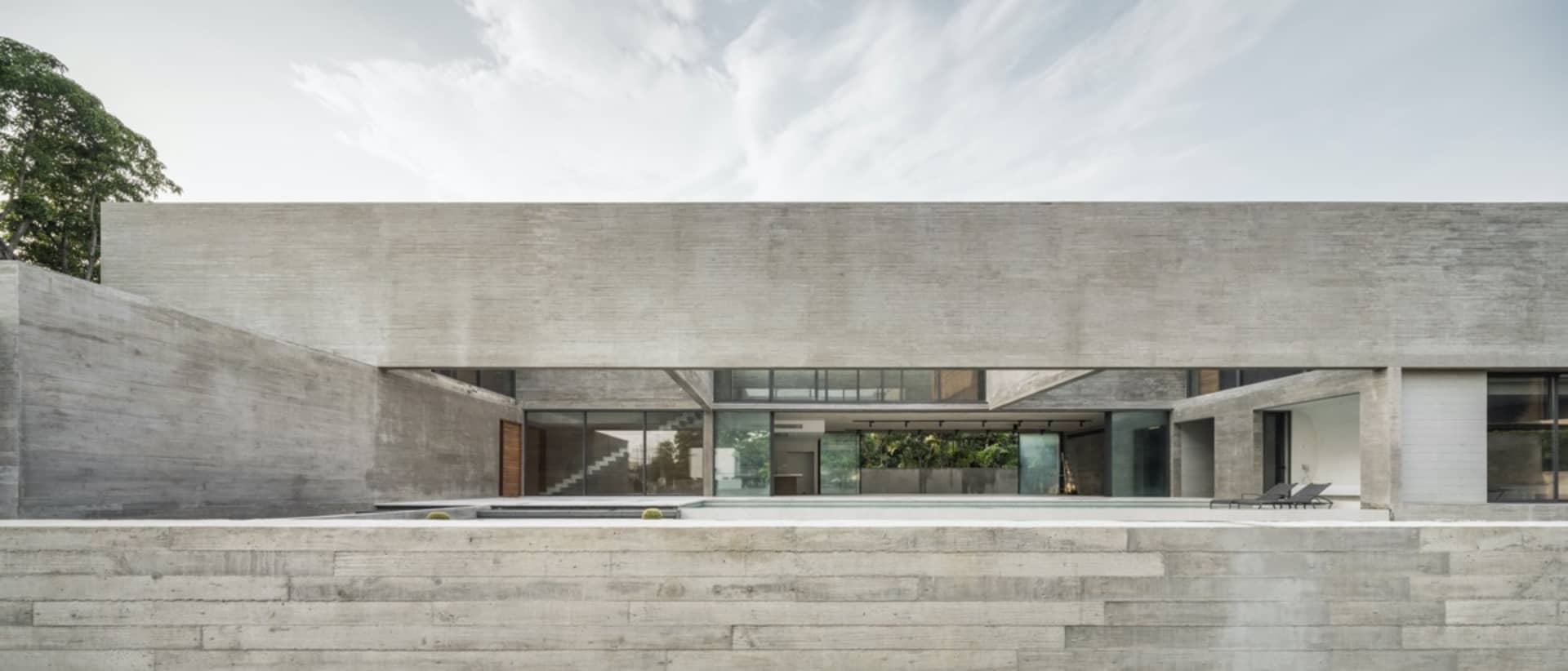 Modern, minimalist house with concrete exterior and large windows.