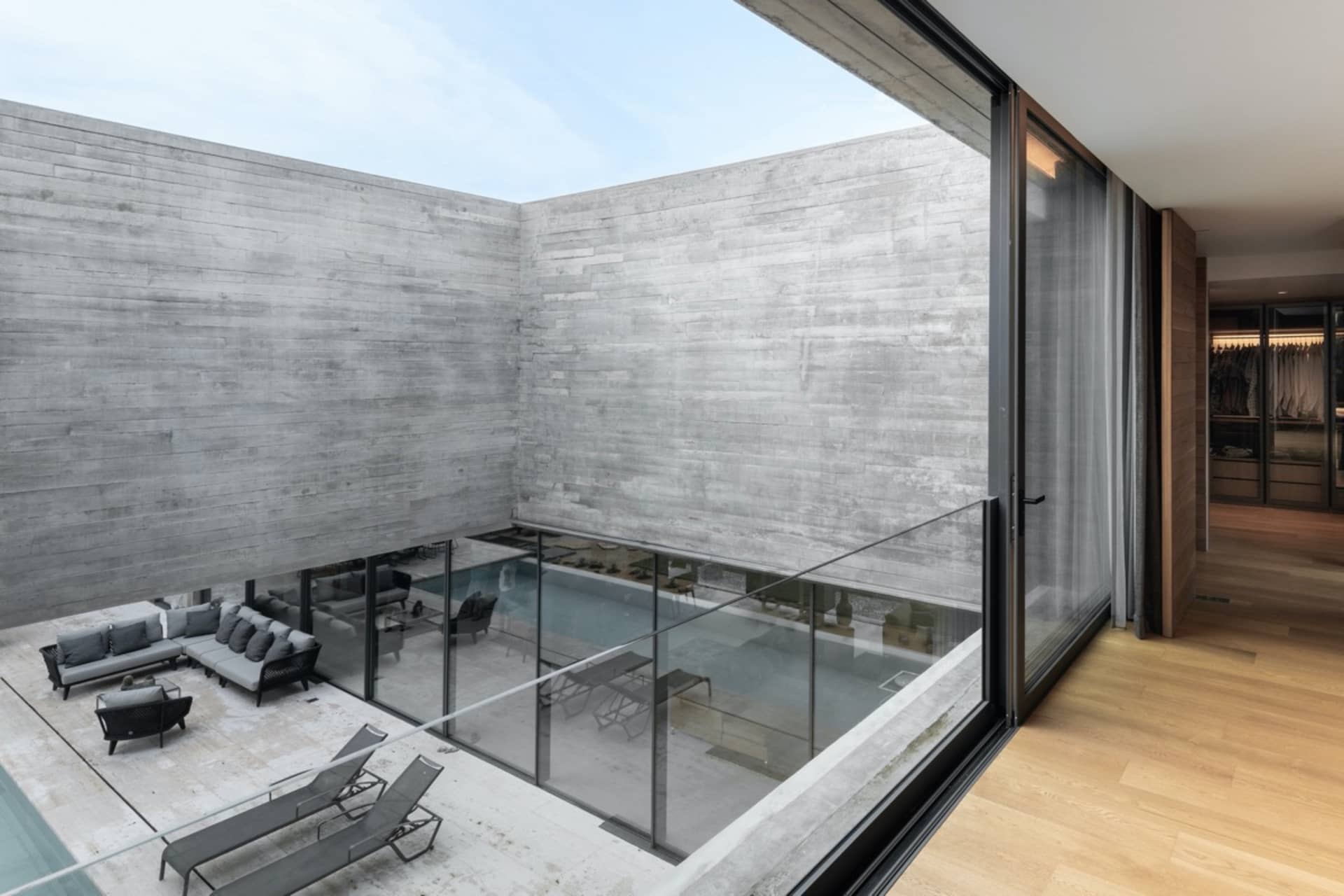 A modern residential interior with concrete walls and glass elements.