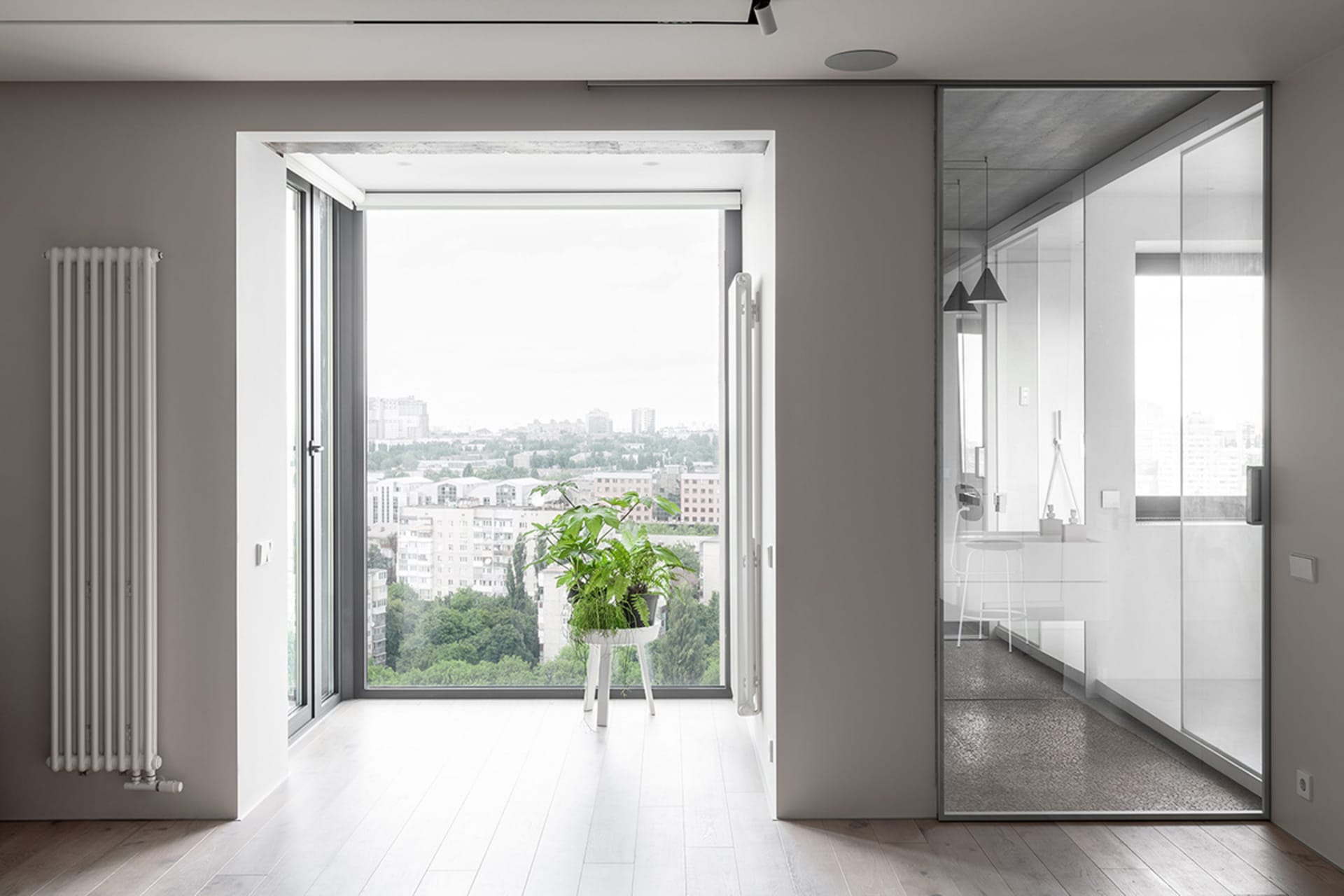 A modern apartment interior with a minimalist design, featuring a large window with a city view, metallic railings, and a gla