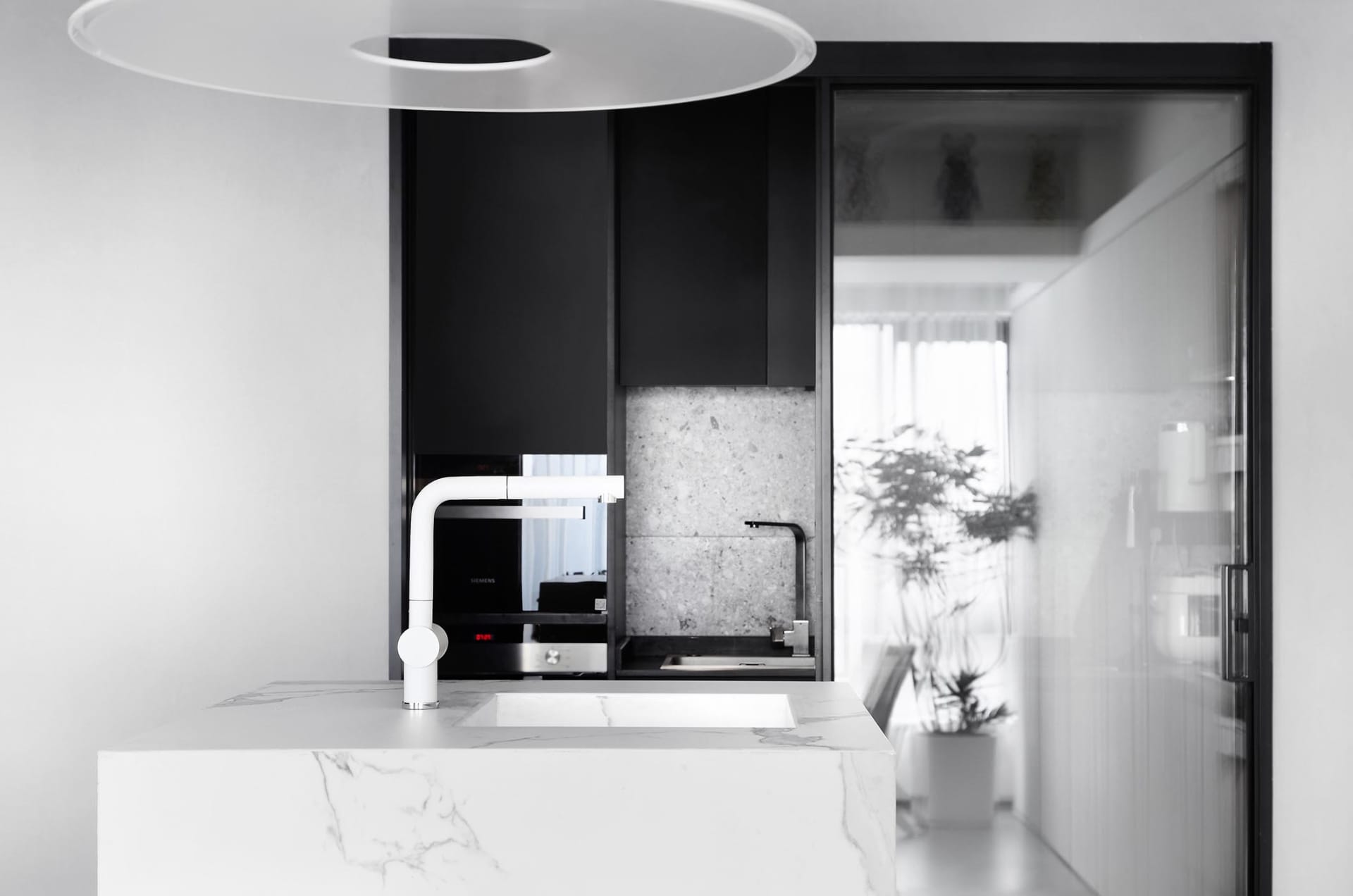 Modern kitchen with black cabinets, white marble countertops, and minimalist design