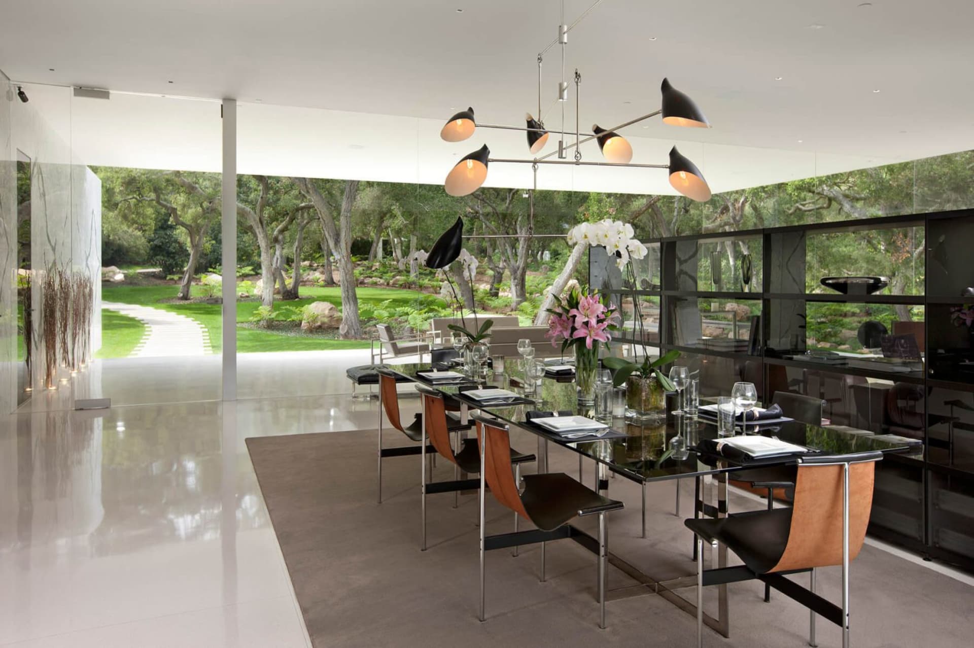 Modern dining room featuring a sleek, minimalist design with a glass chandelier and stylish furniture.