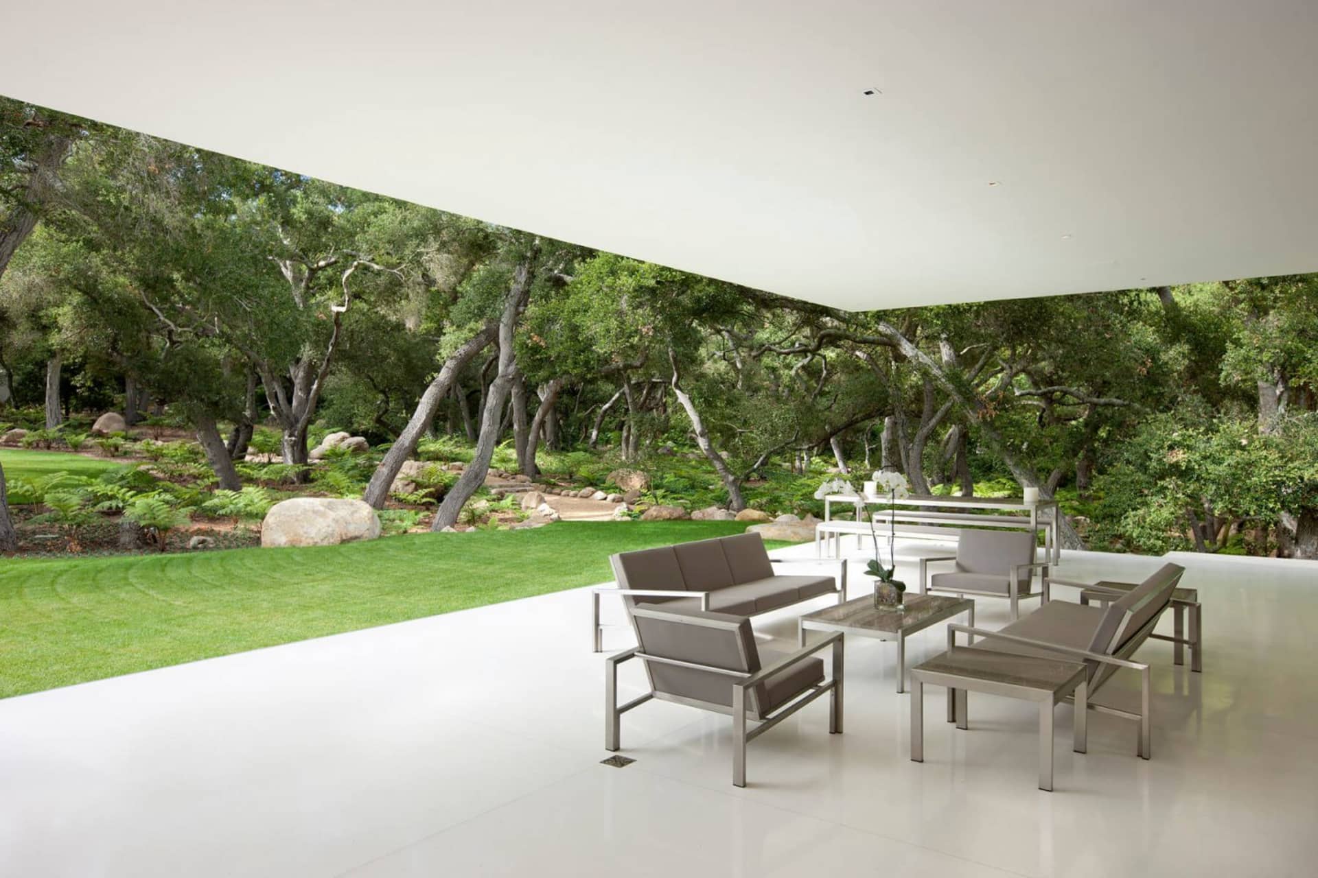 A contemporary living room featuring modern furniture with metal and glass elements on a white floor.