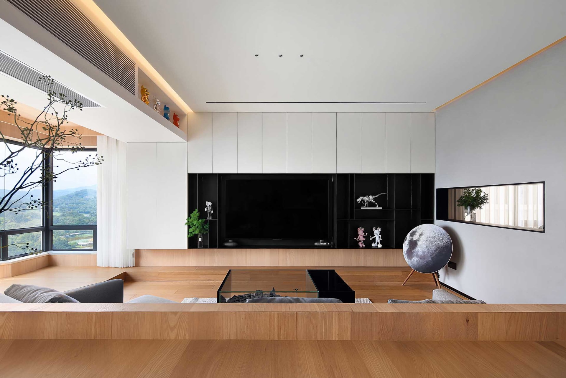 Modern living room with wood flooring, glass coffee table, and metal accents