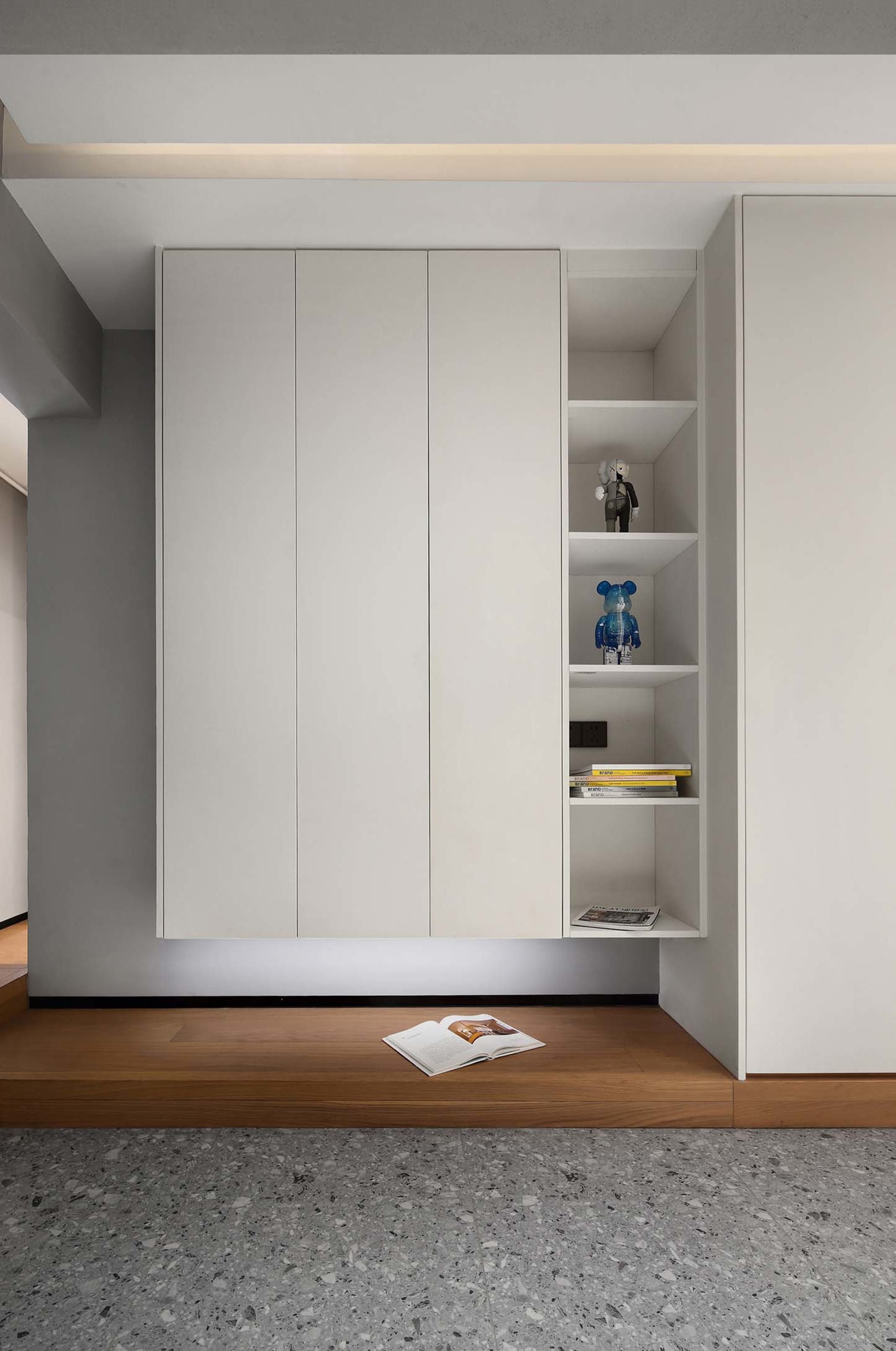 Modern minimalist storage shelves with white doors, featuring open shelving and decorative items on the right side.