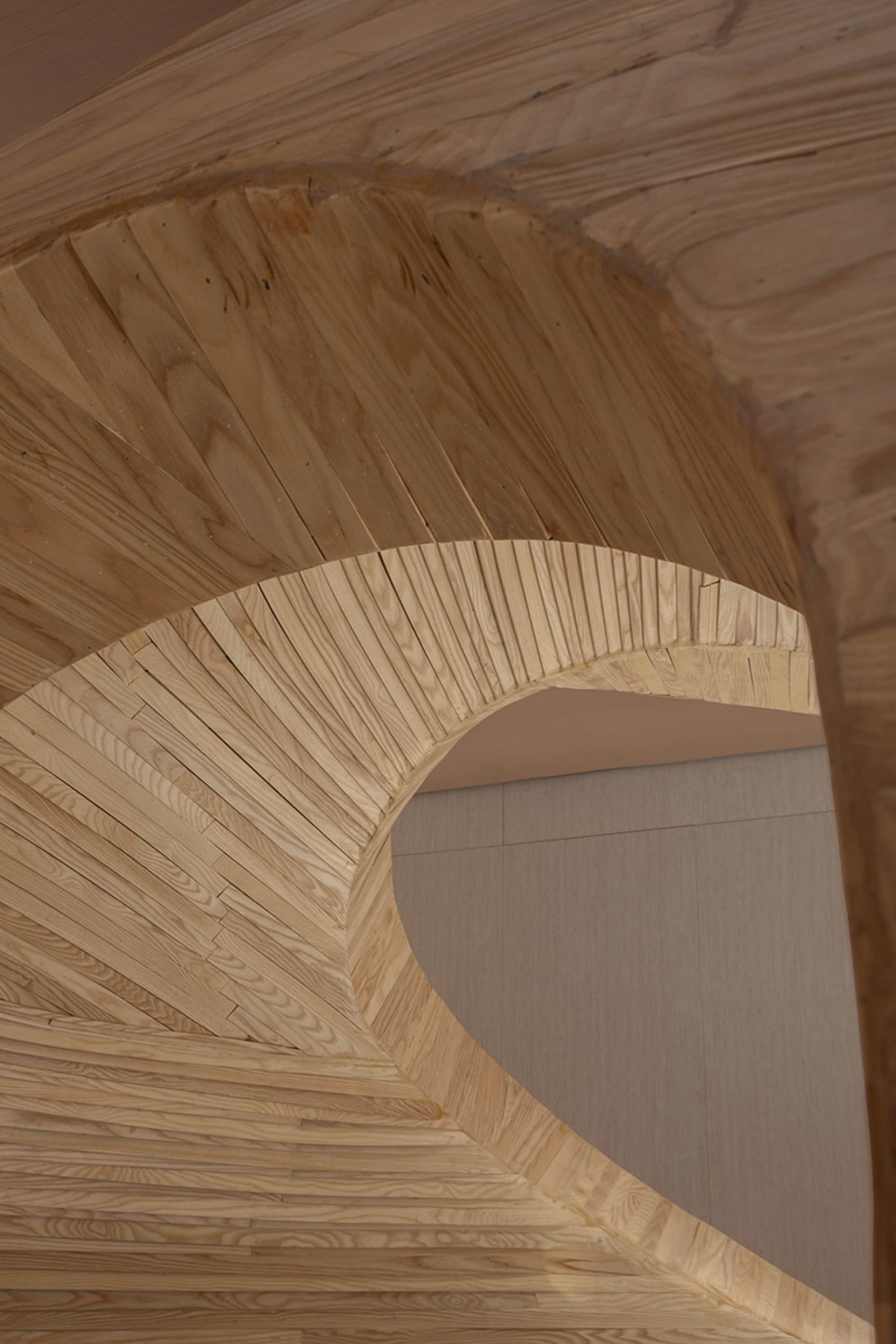 A minimalist wooden staircase with curved steps.