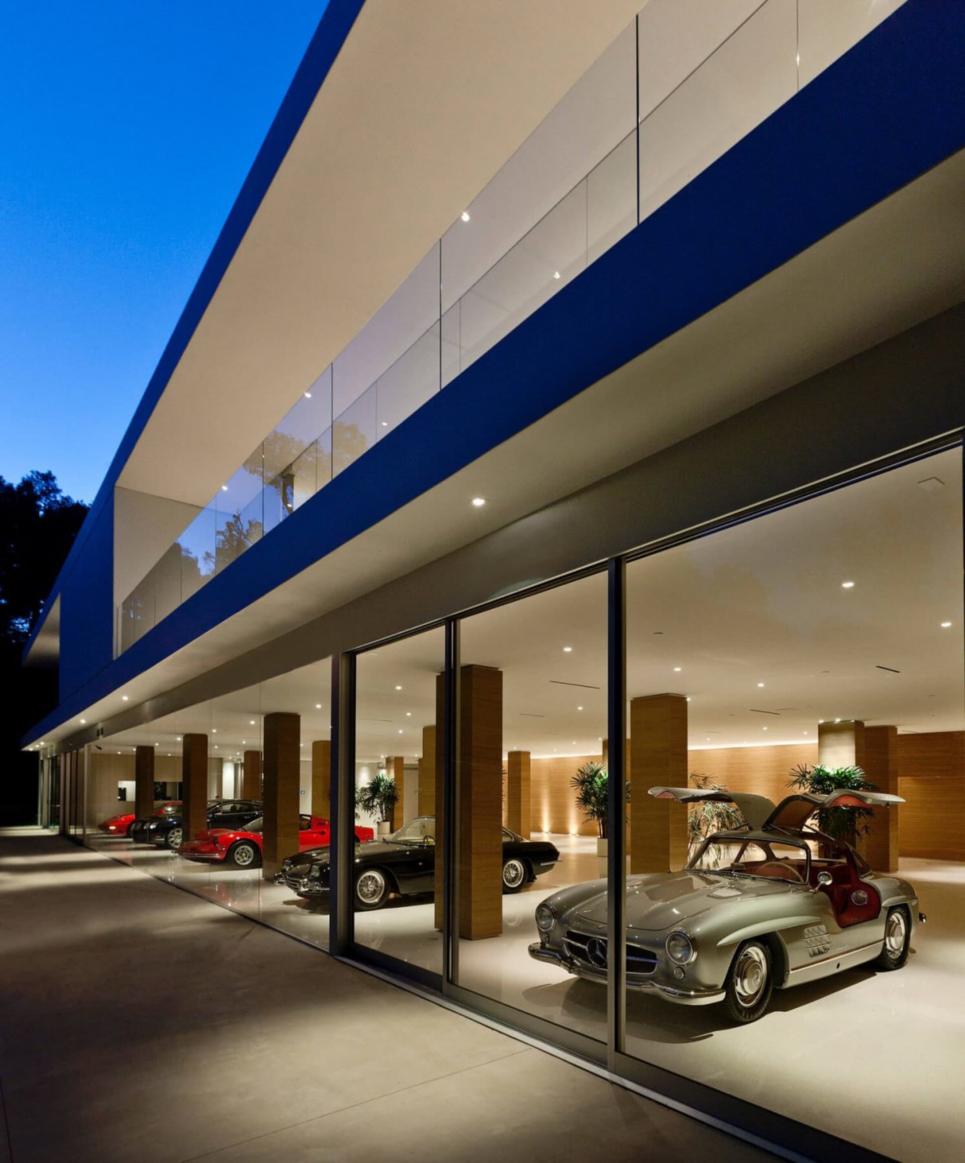 A modern car showroom with glass walls displaying various cars.