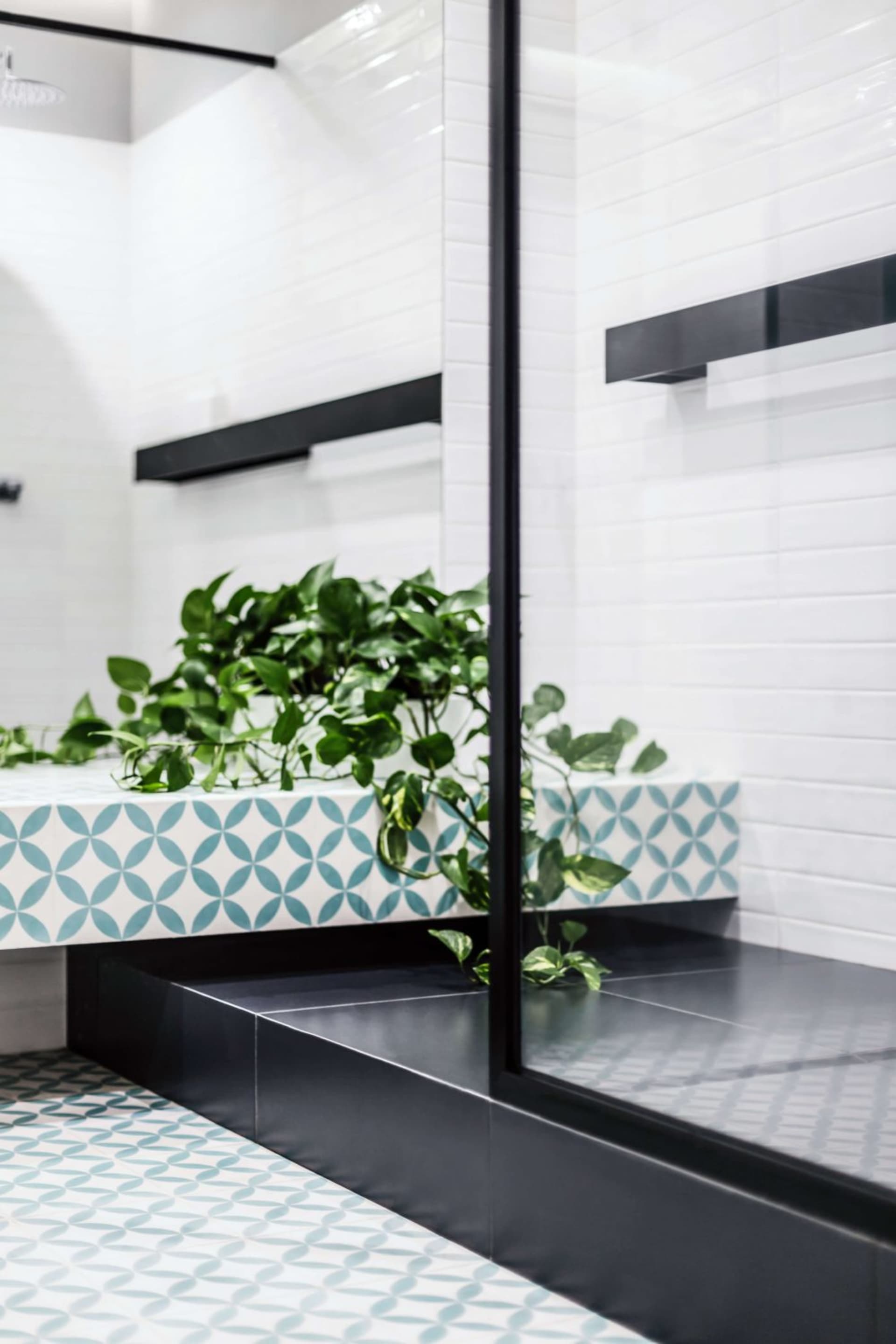 A modern bathroom featuring patterned ceramic tiles and glass fixtures.