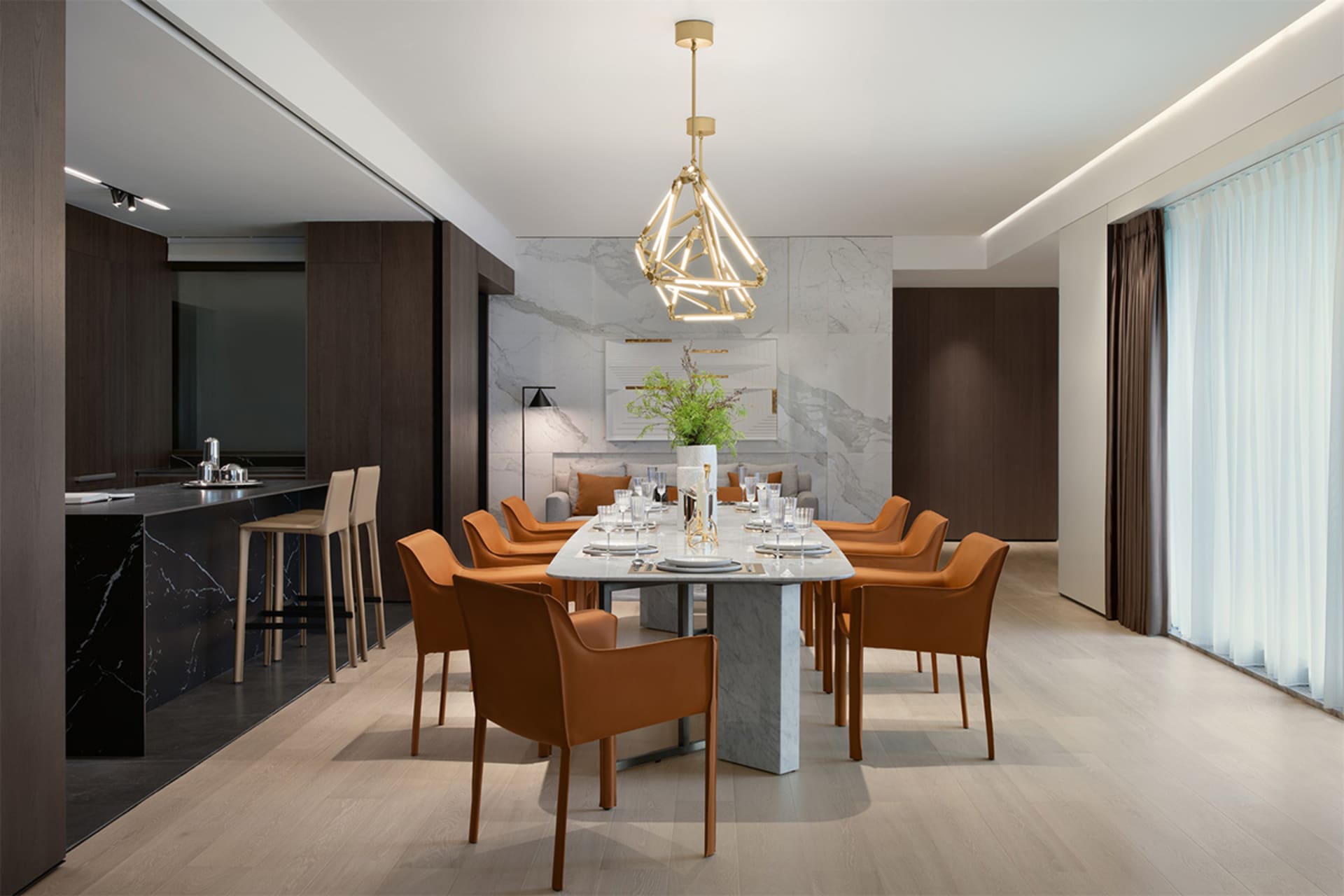 A modern dining room featuring a marble table surrounded by orange chairs and a geometric chandelier.