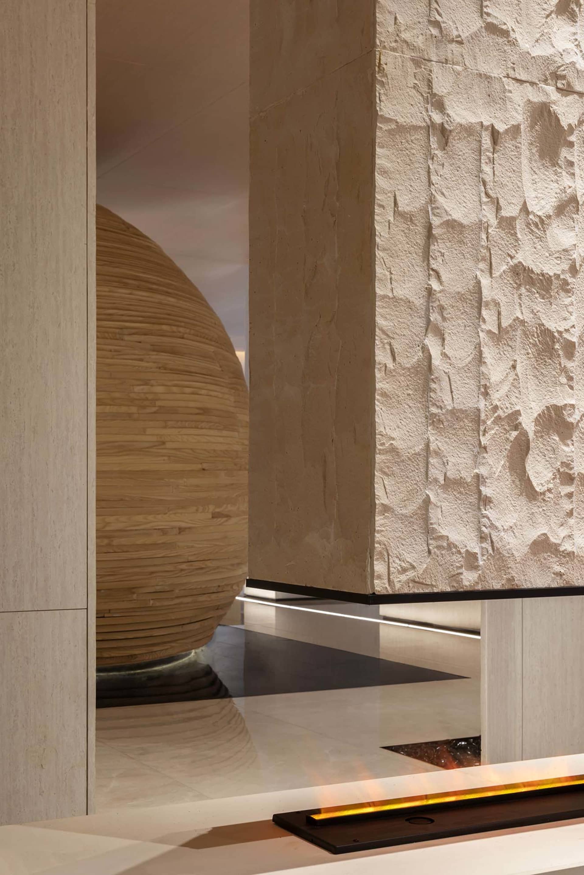 A modern living room with a bamboo ball sculpture and stone walls.