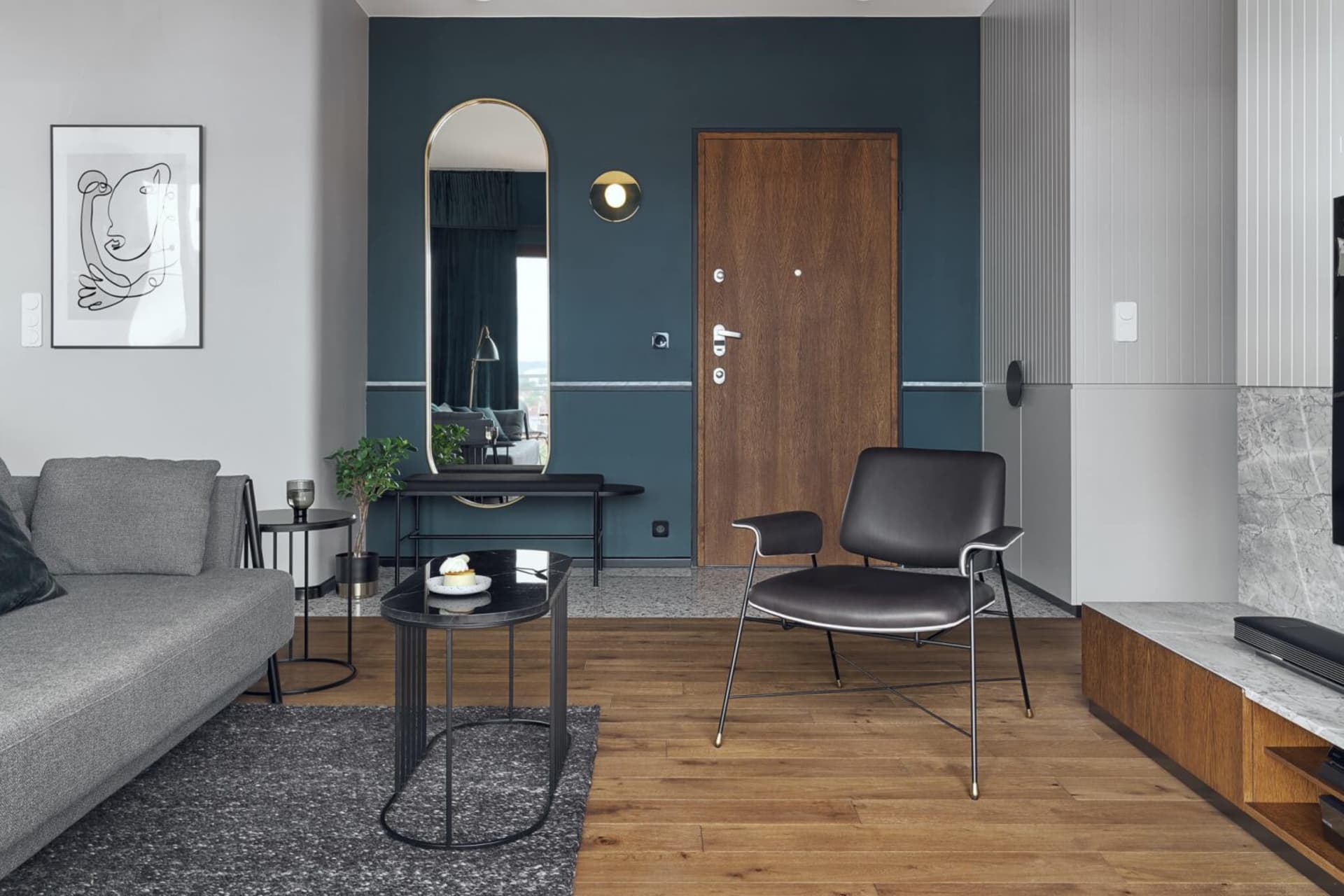 Modern living room featuring a wooden floor, metal coffee table, leather armchair, and minimalist decor.