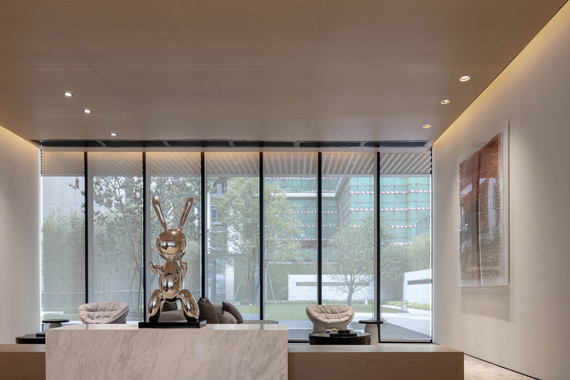 Modern lobby with a glass wall and a metallic rabbit sculpture.