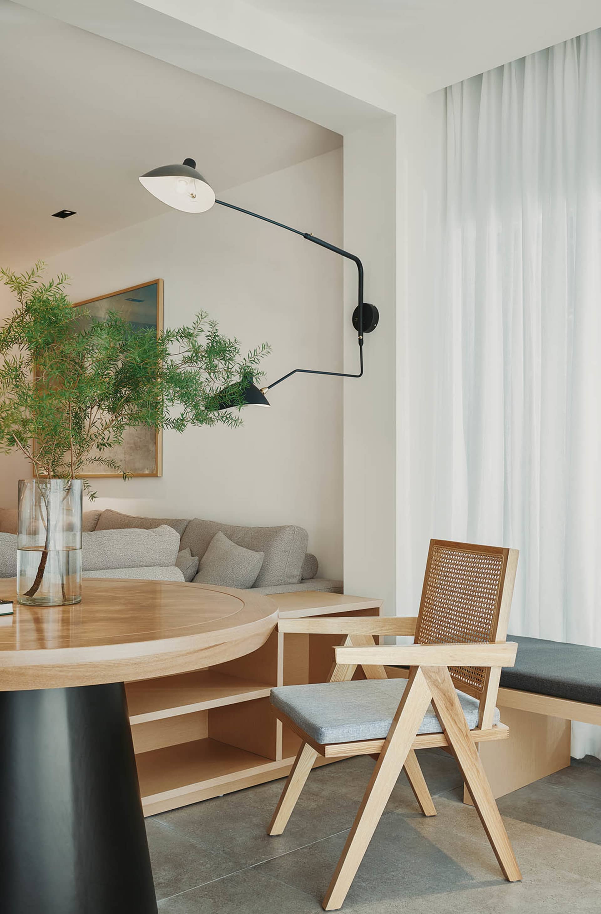 Modern residential interior featuring wood furniture, fabric seating, and glass windows.