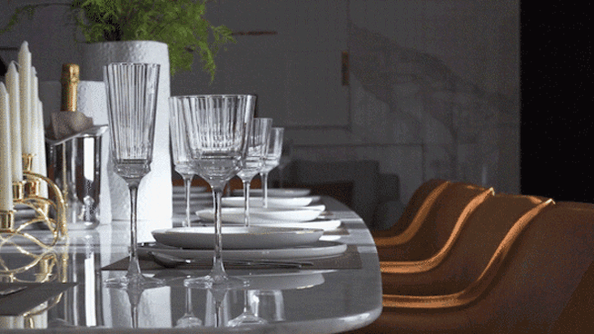 A beautifully set dining table with crystal wine glasses and elegant tableware.