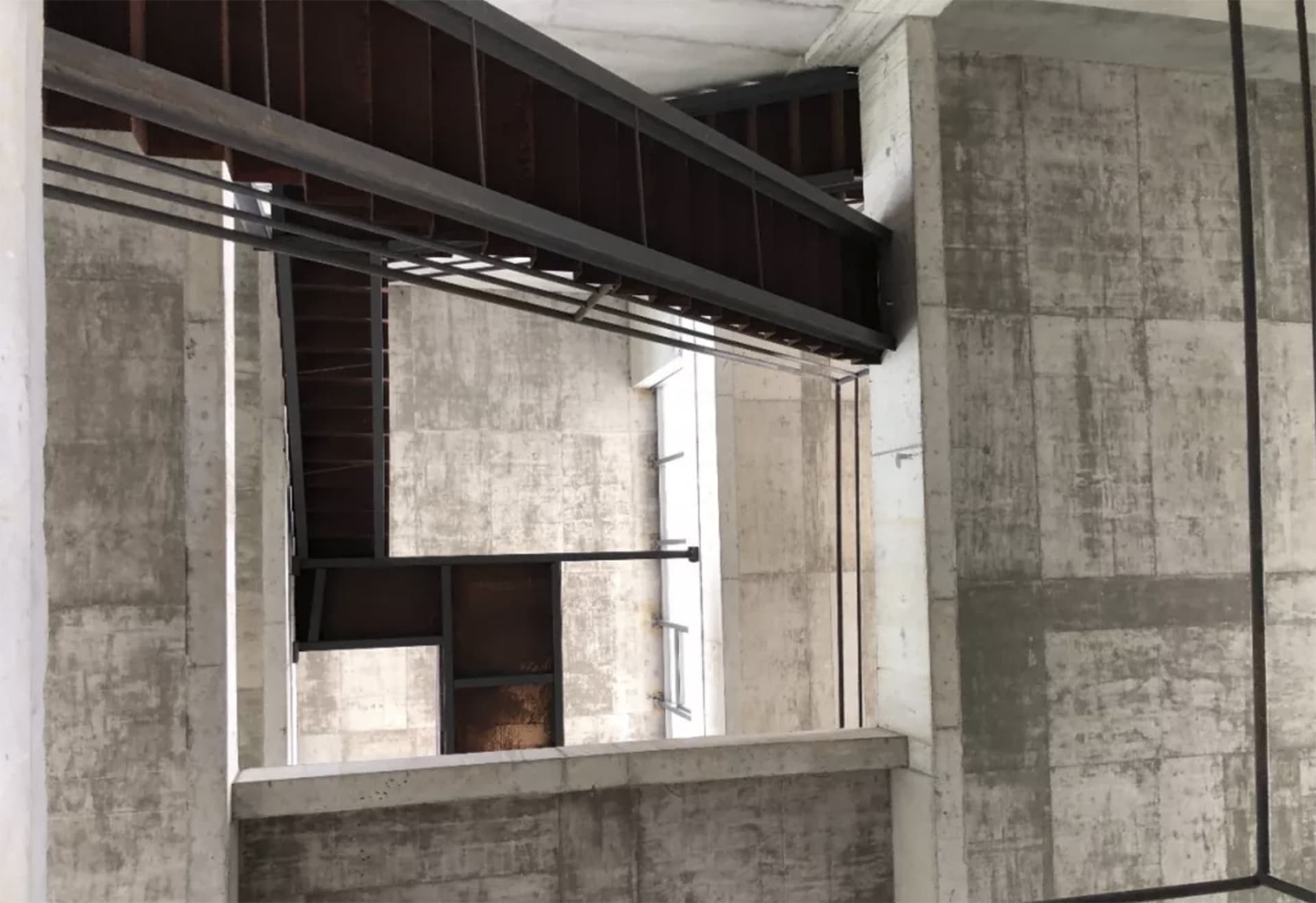 A modern concrete and steel staircase with a metal handrail.