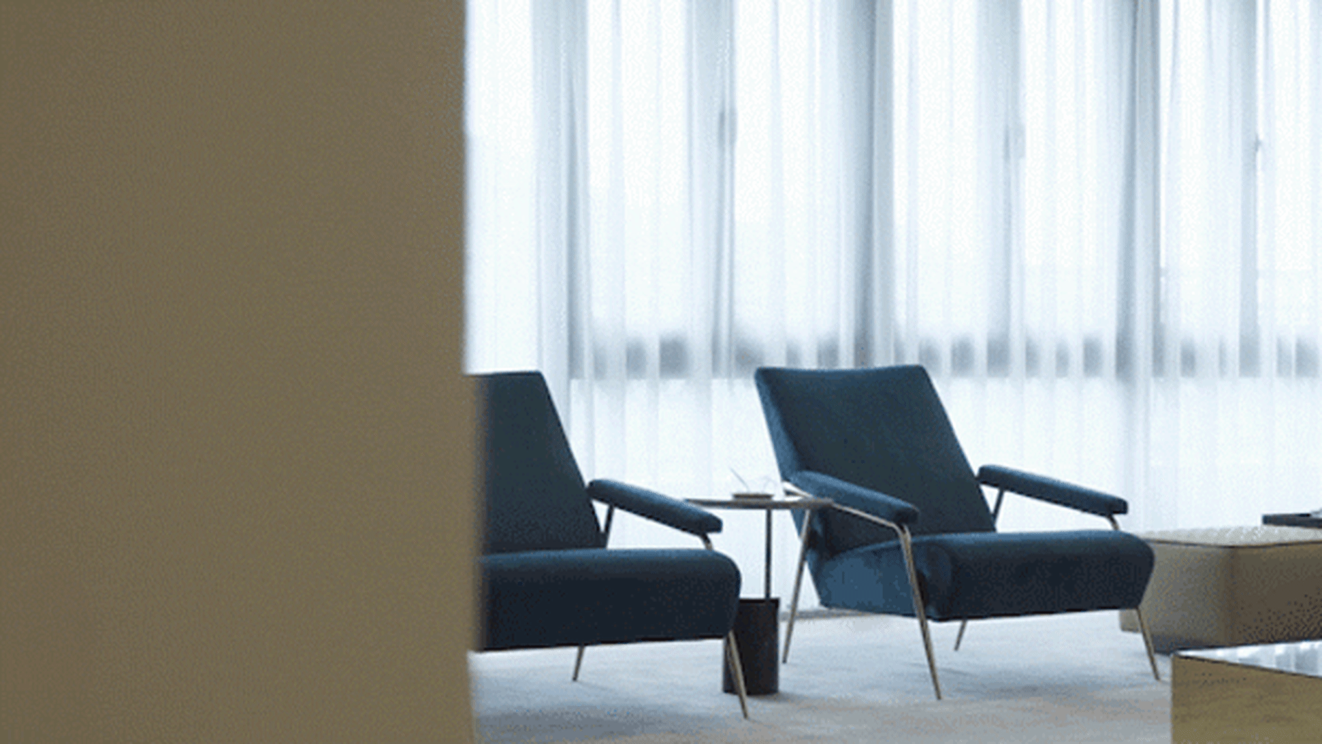 Modern blue armchairs with white curtains in a contemporary interior design setting.
