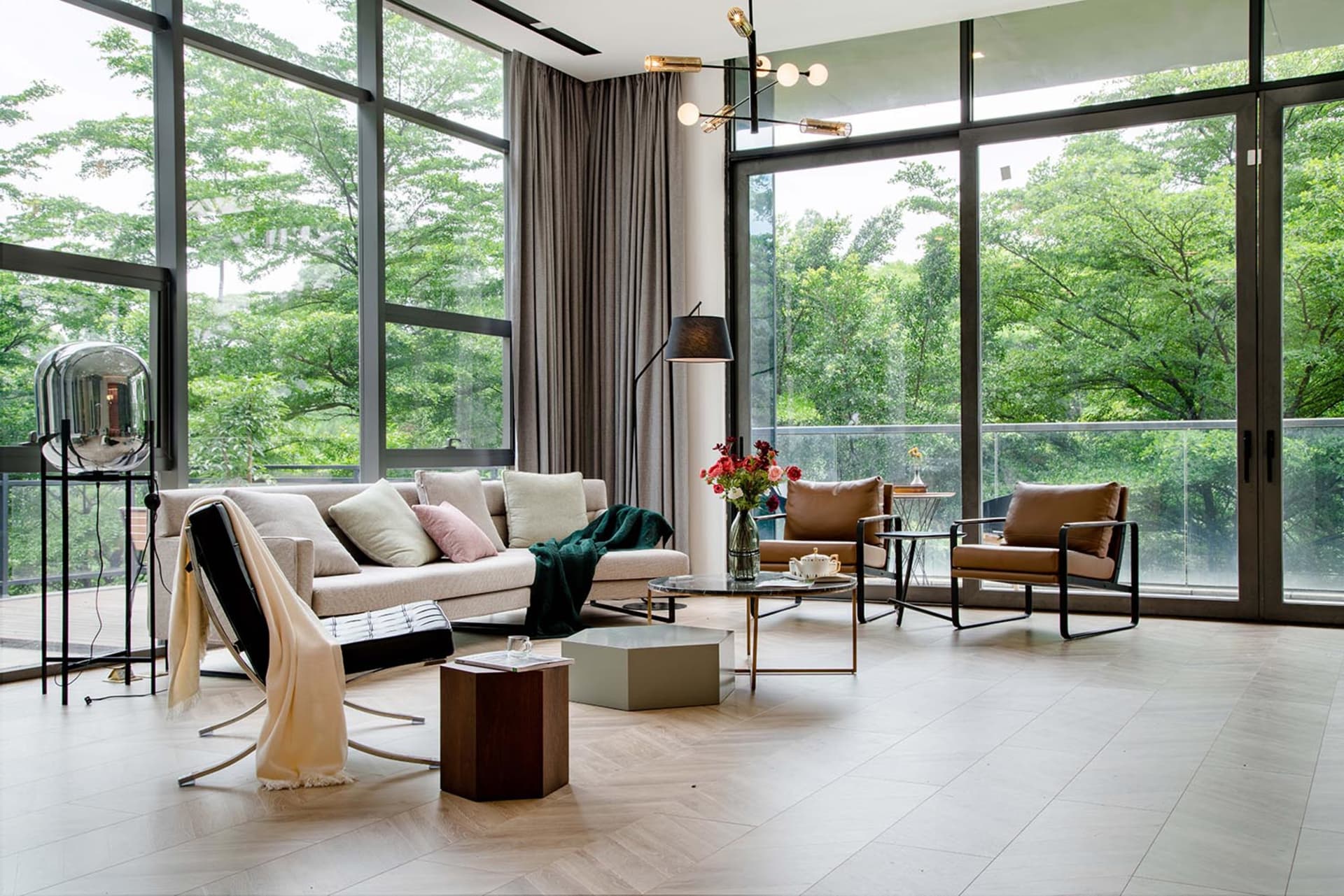 A modern living room featuring wood flooring, leather chairs, and a glass coffee table.