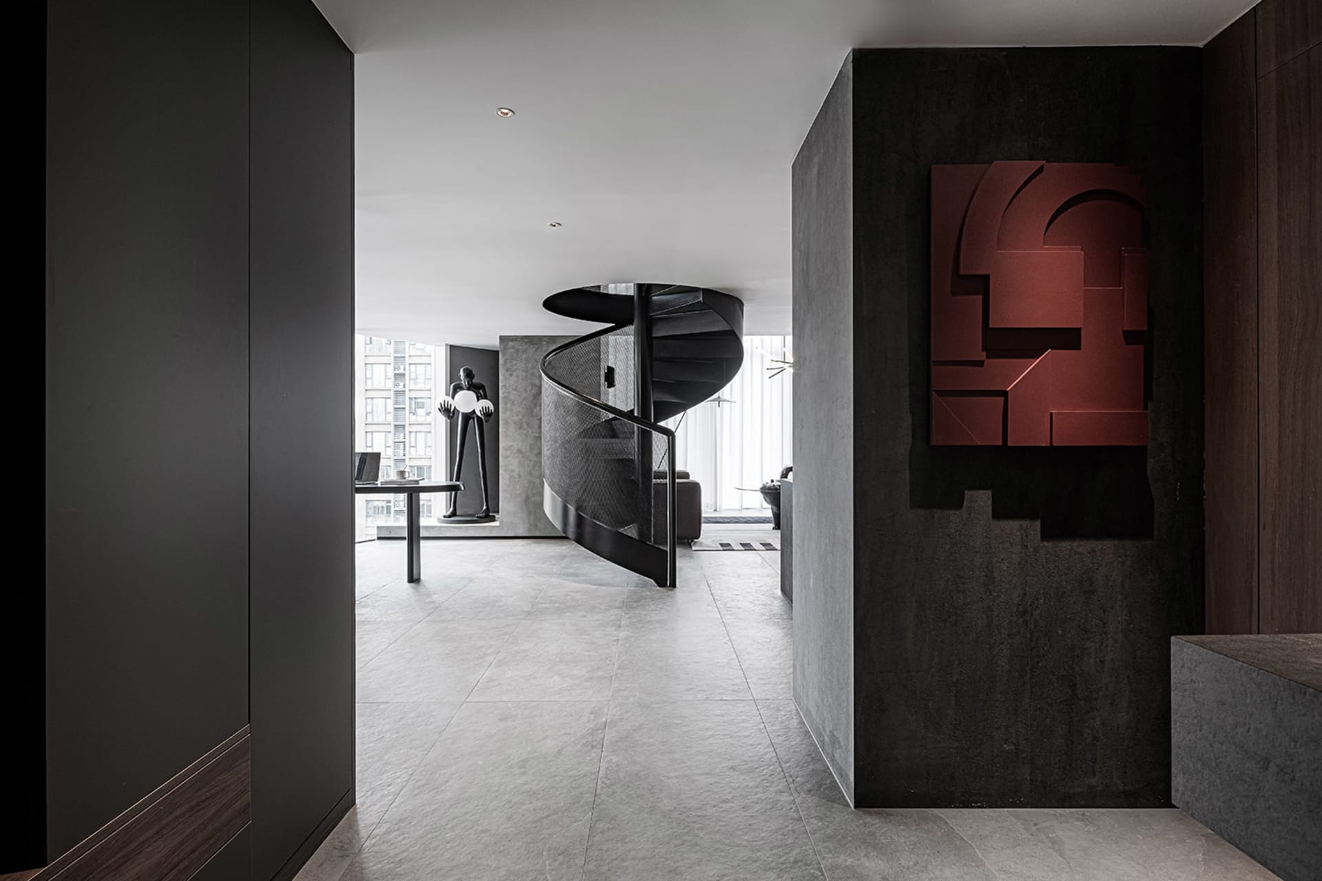 A modern, industrial-style lobby with a spiral staircase, concrete walls, and a geometric mural.
