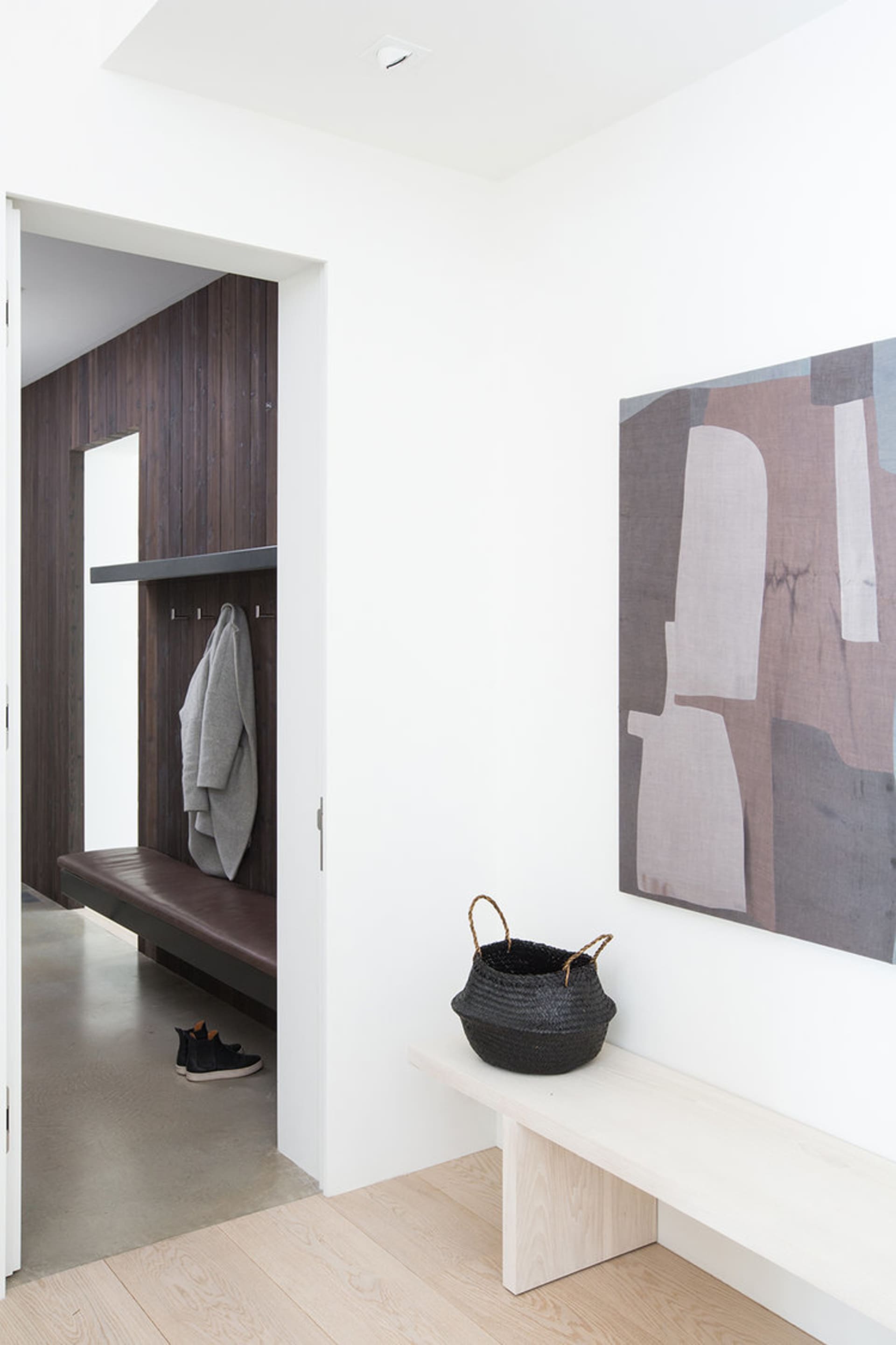 Modern entry way featuring wooden flooring, bench, and coat rack.