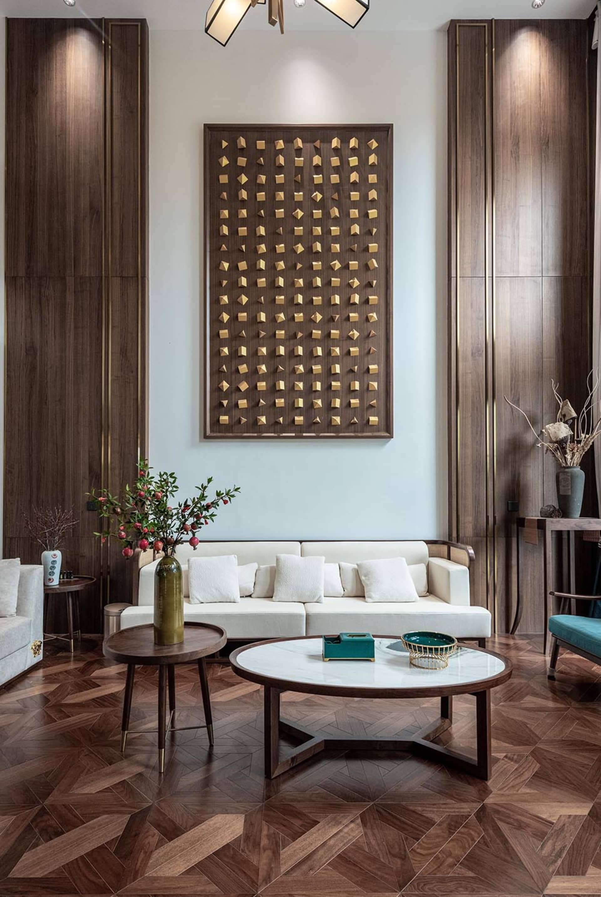 A modern white sofa with two round marble tables and plants on side tables in a room with wooden walls and floor.