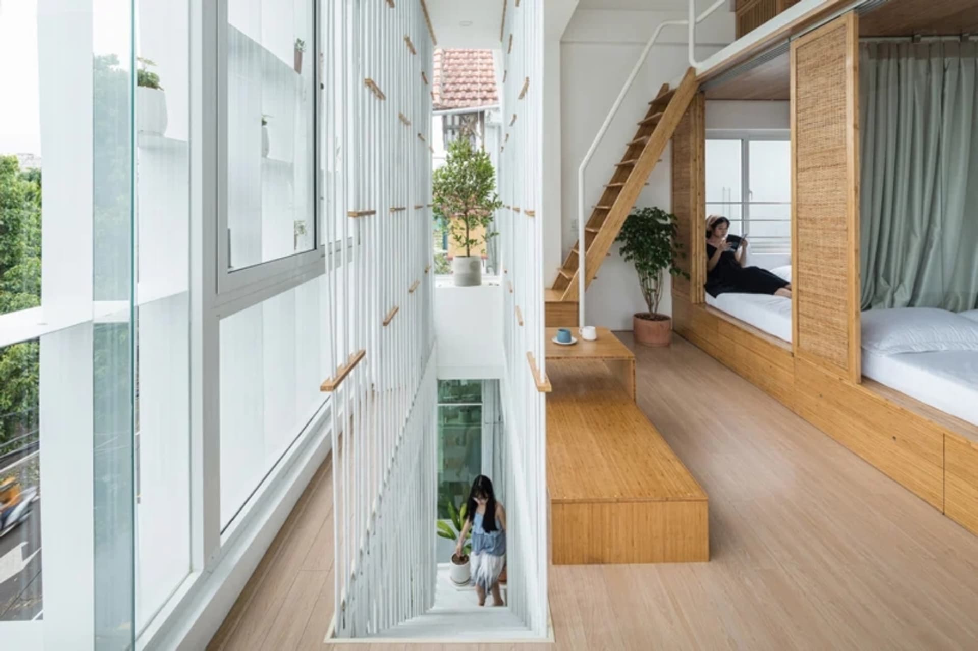 A modern, white-designed indoor space featuring wooden furniture and flooring, a white screen divider, and a potted plant.