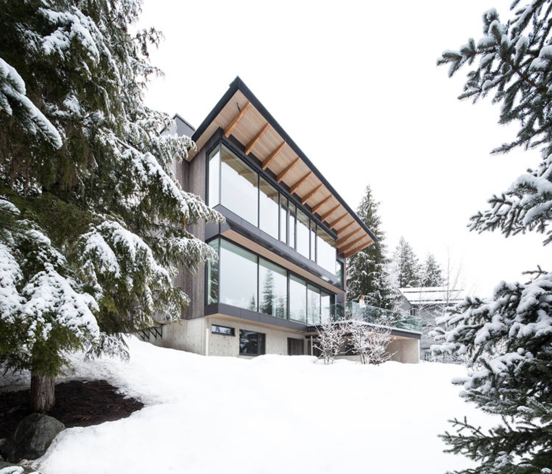 A modern lodge with wood and glass construction amidst a snowy landscape.