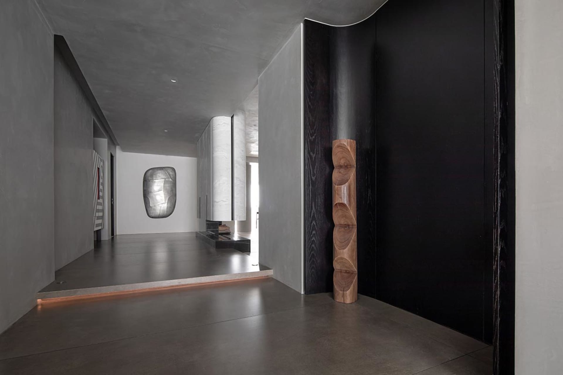 A modern interior space with concrete walls and a wooden sculpture