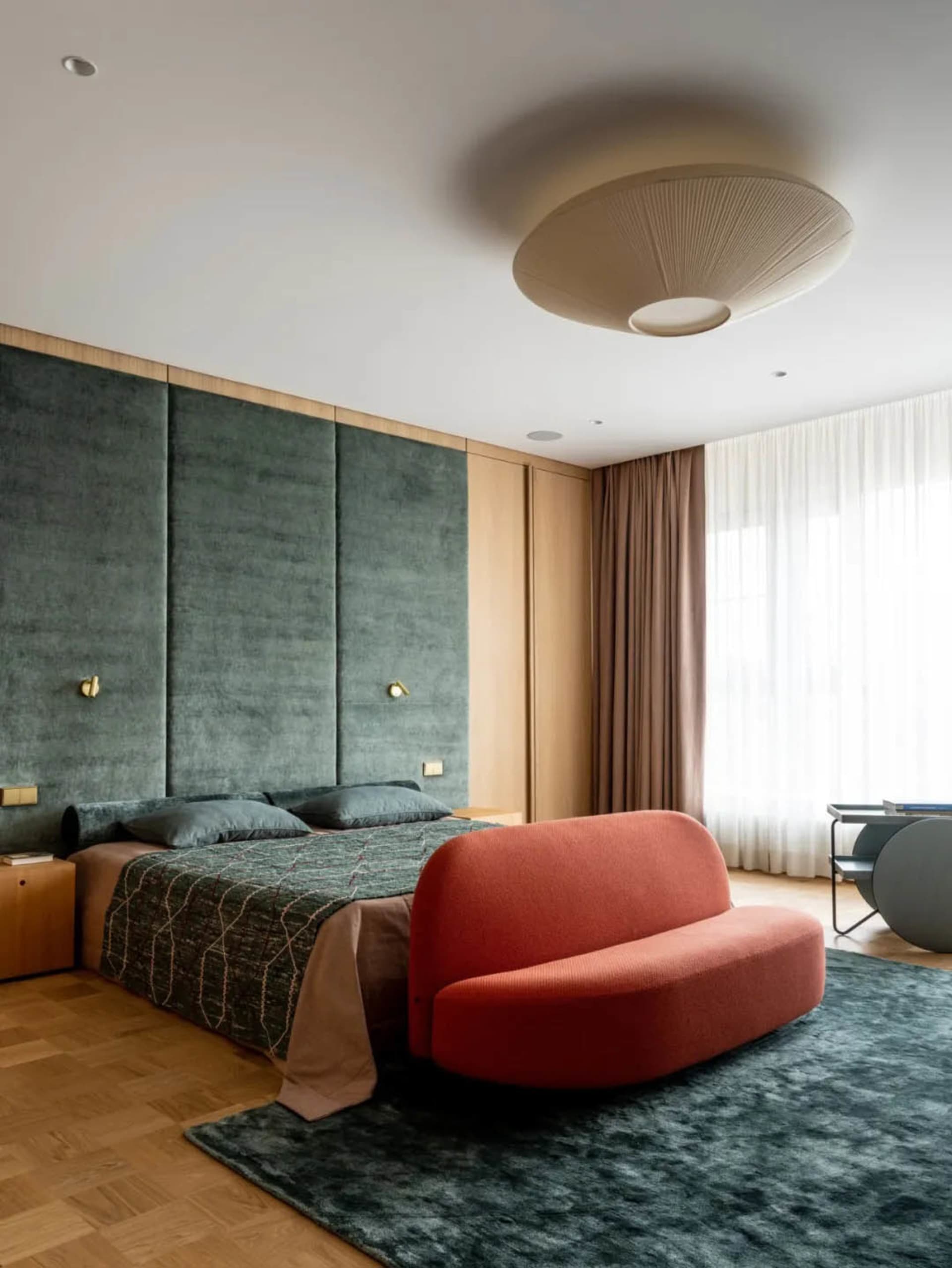 Modern minimalist bedroom with velvet bedding, wooden paneling, and wood floors.