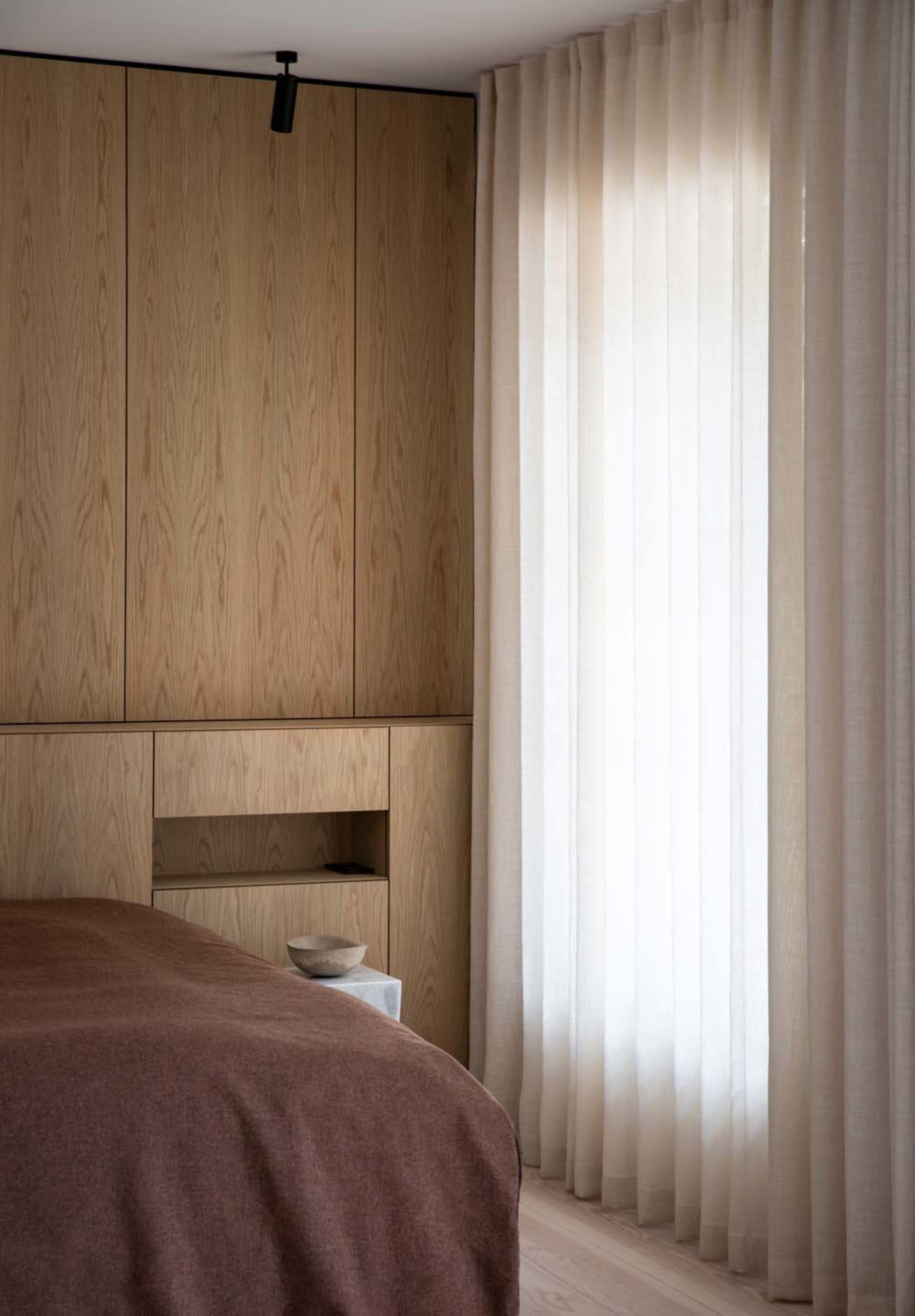 Minimalist bedroom featuring wooden cabinets and curtains