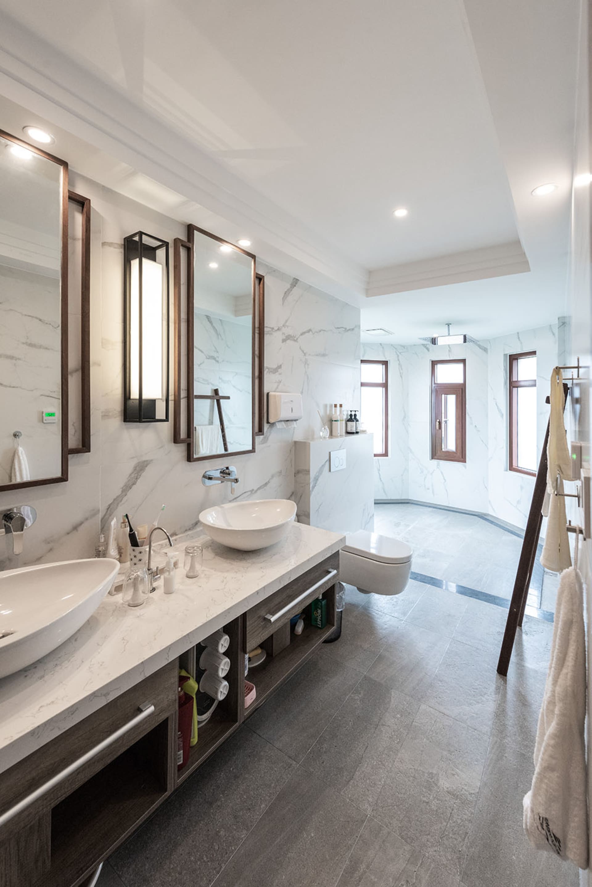 Modern bathroom with marble tiles, two sinks, and a toilet.