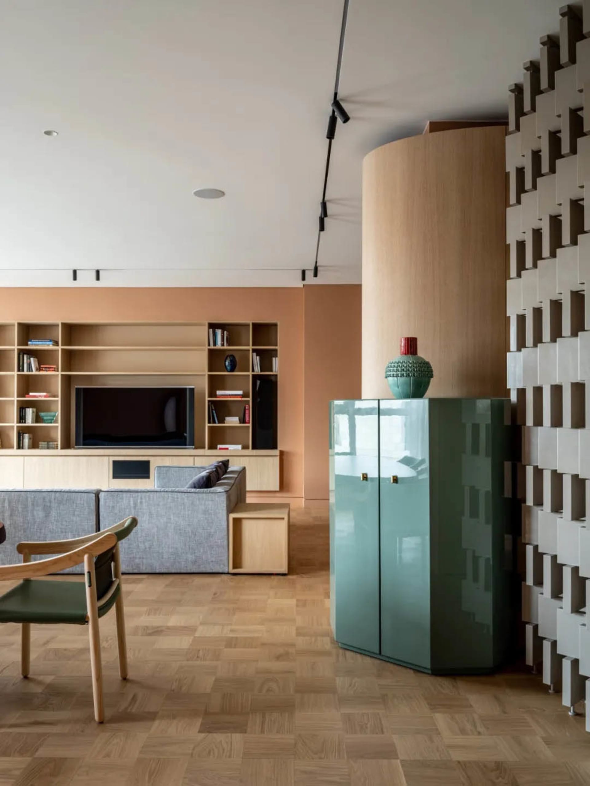 A modern living room with a gray sectional sofa, wooden floor, and bookshelves.