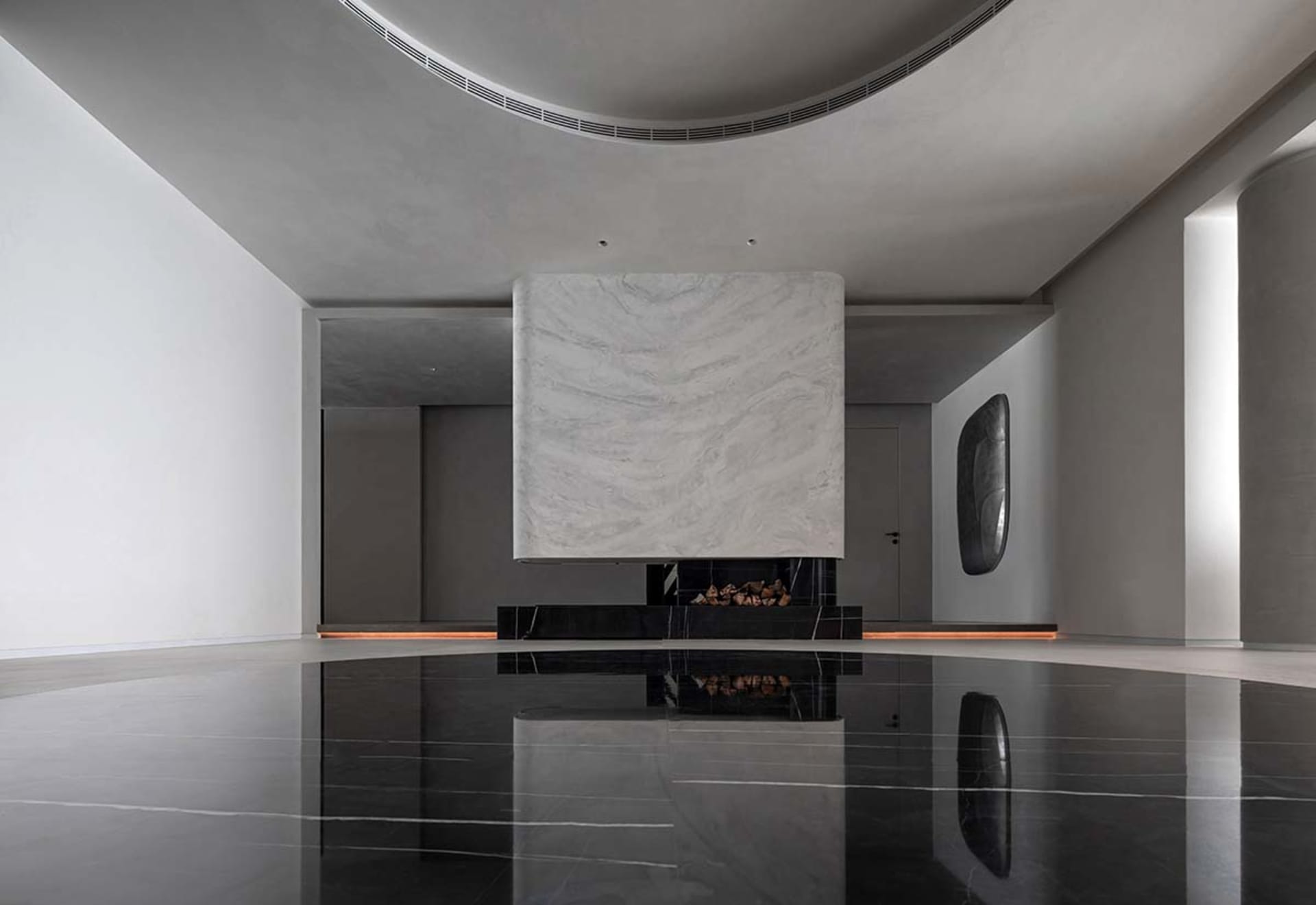 An elegantly designed living room featuring a modern fireplace enclosed in a black marble slab with a glass insert.