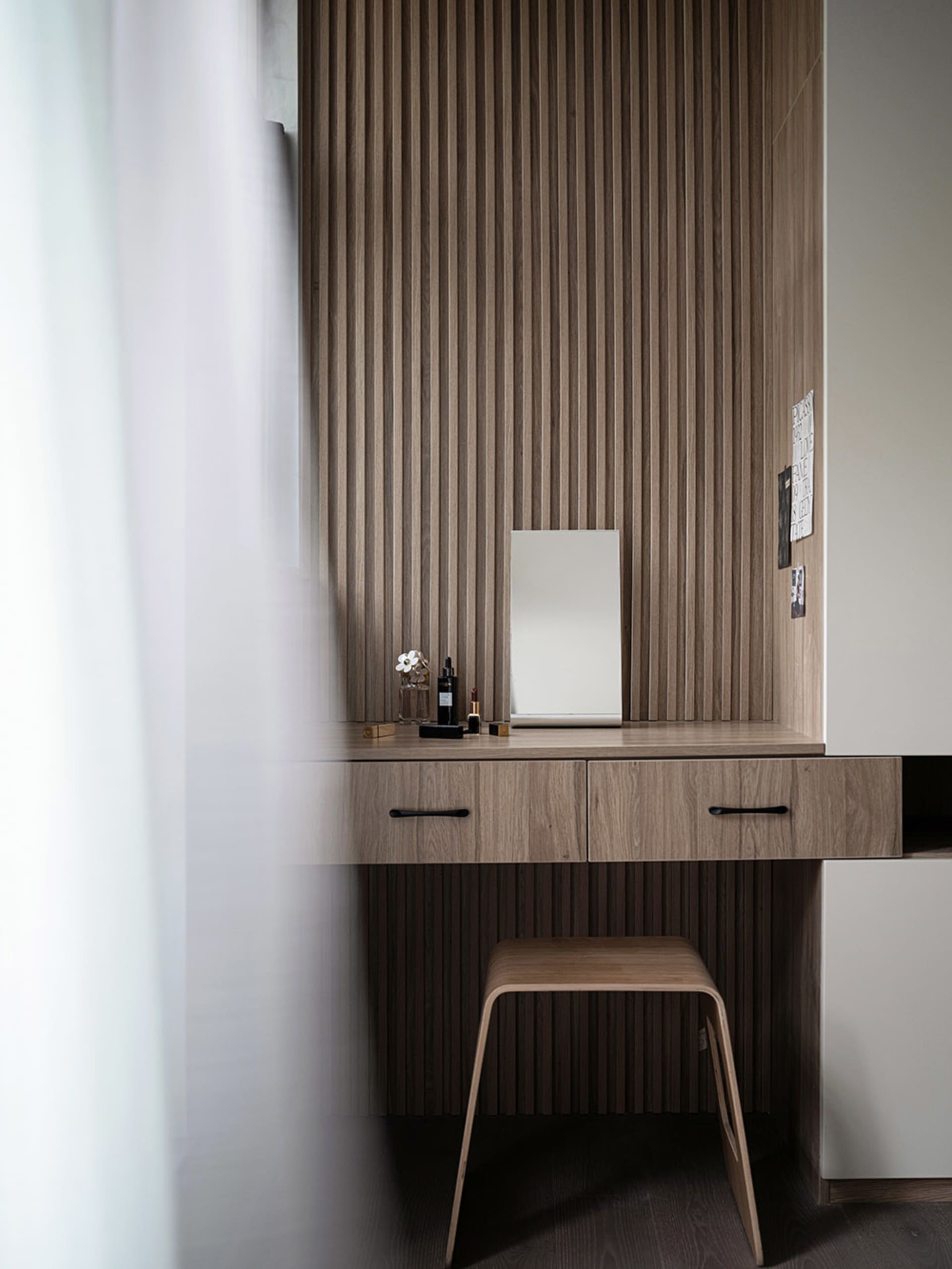 A modern wooden dresser with a minimalist design, featuring a mirror, drawers, and a stool.