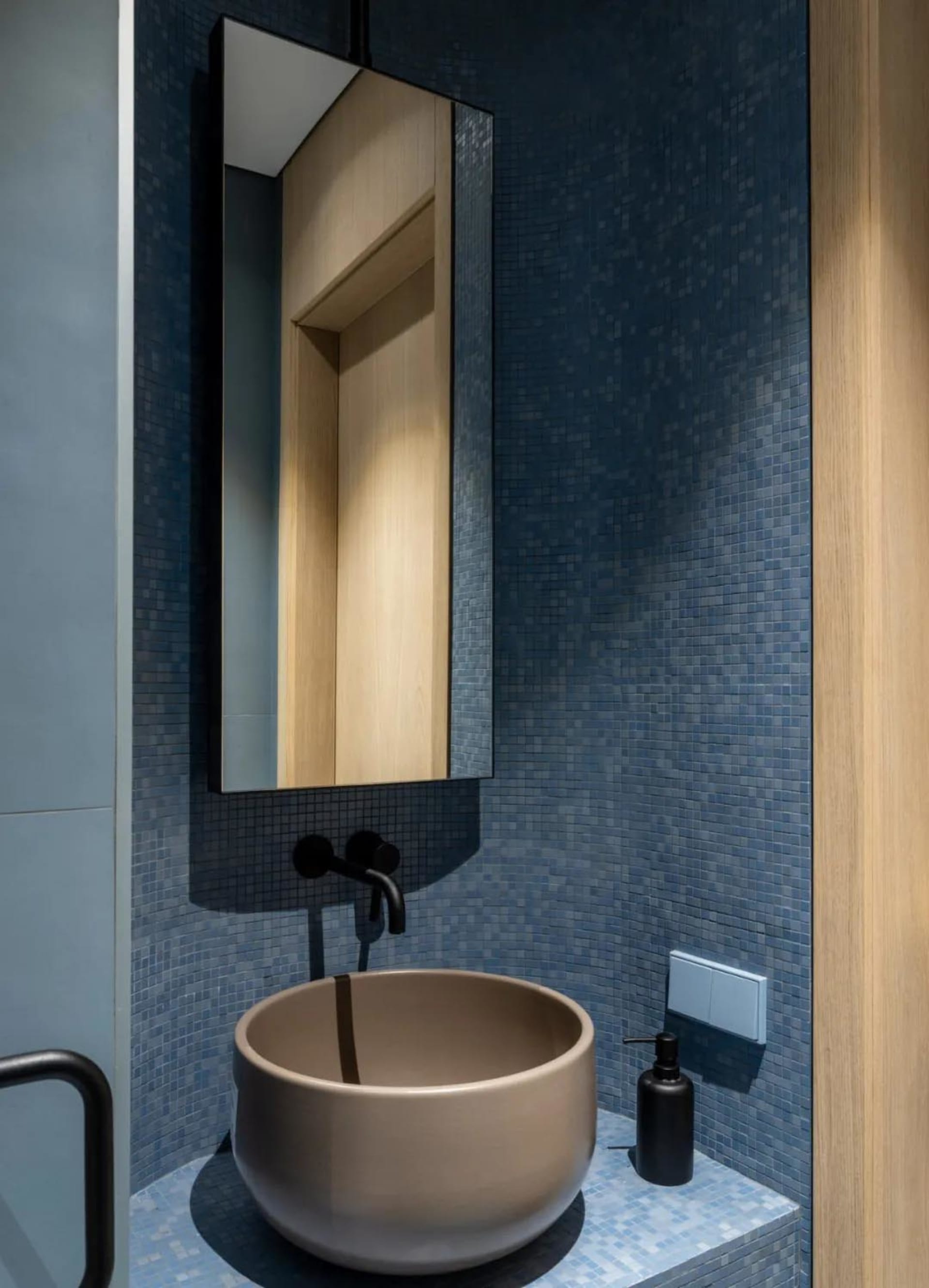 Modern minimalist bathroom adorned with blue mosaic tiles and a sleek ceramic basin against a light-colored background, creat