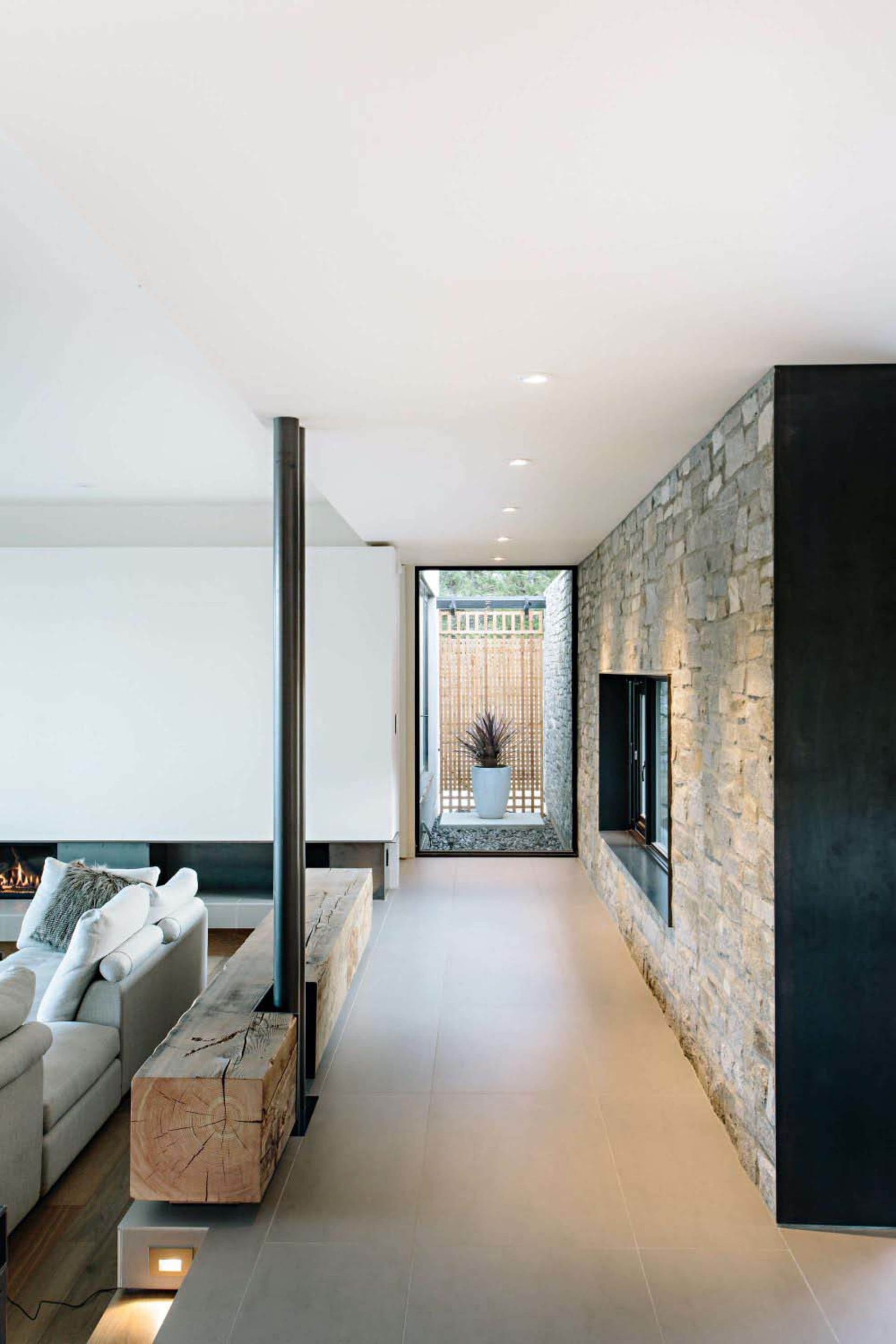 Modern living room with stone walls, concrete floor, and wooden accents