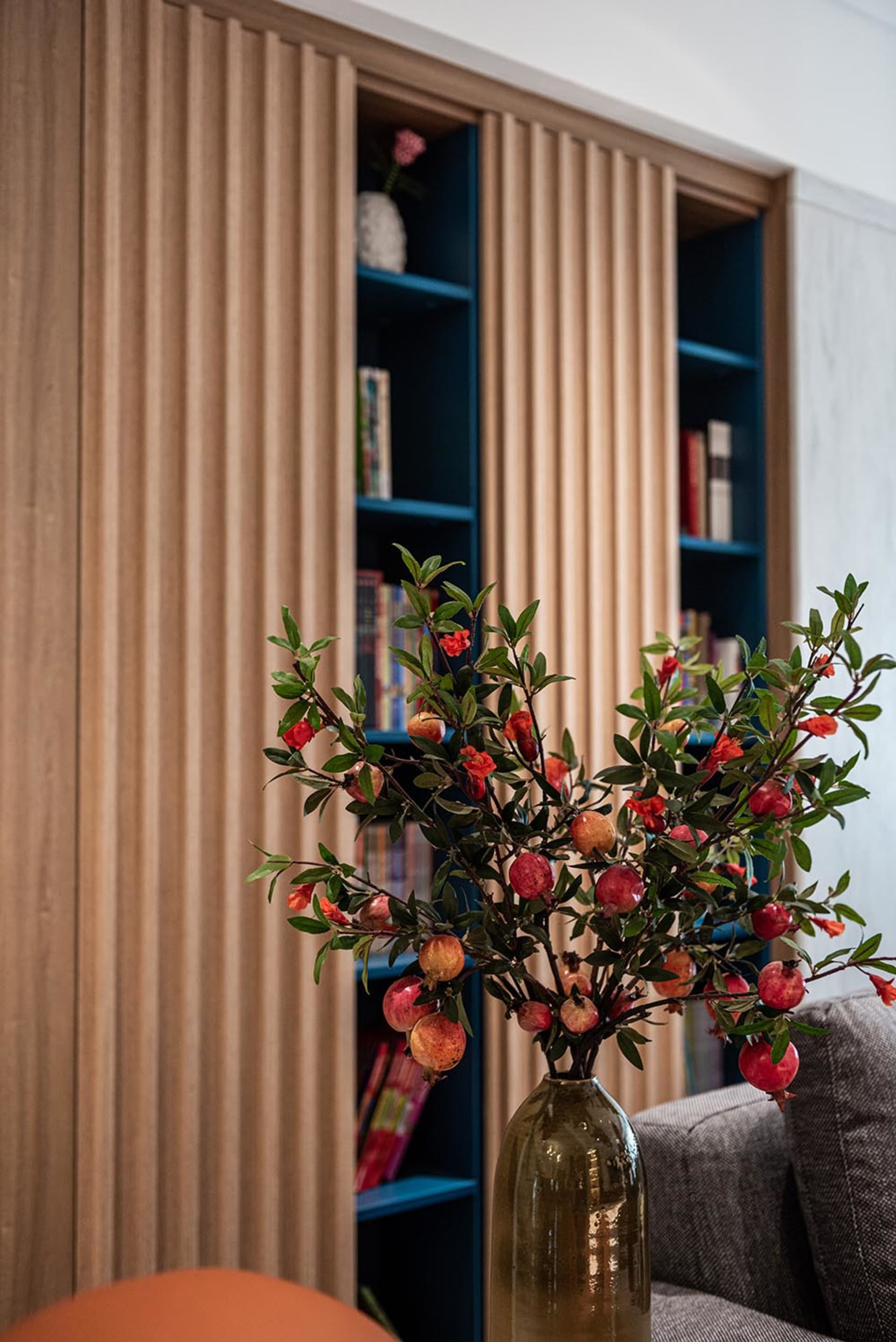 A modern living room featuring a wooden shelving unit filled with books and decorative items.