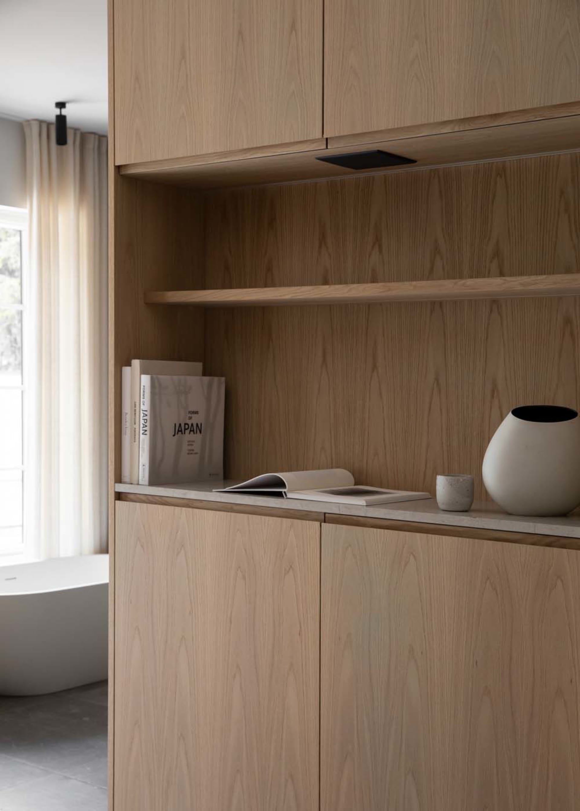 A minimalist interior space featuring wooden shelves and a bathtub with curtains.