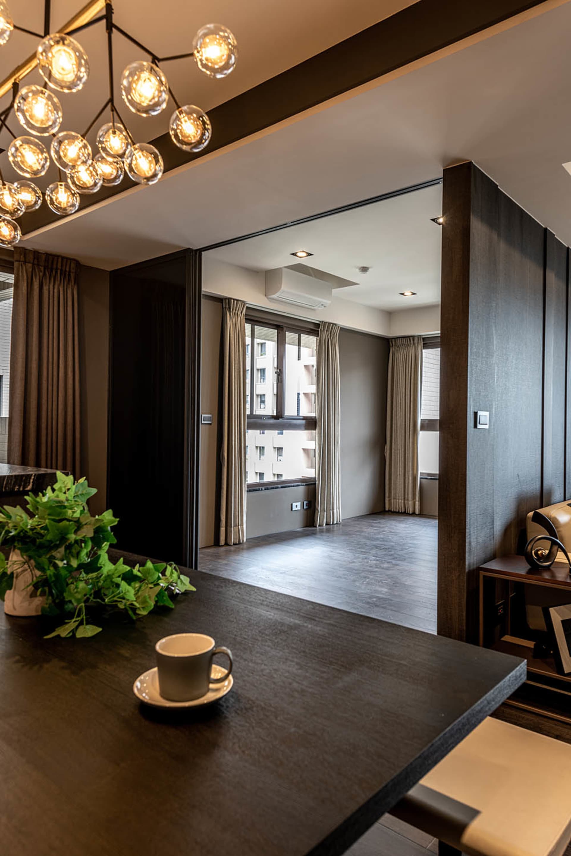 Modern apartment living room with wood laminate flooring and beige curtains by the window.