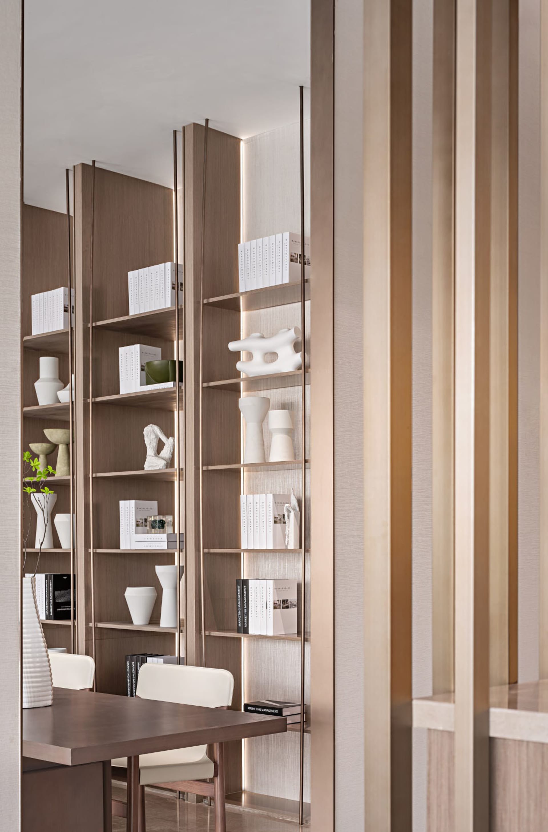 A modern bookshelf adorned with various art pieces and vases, enclosed by wooden panels with metallic accents.