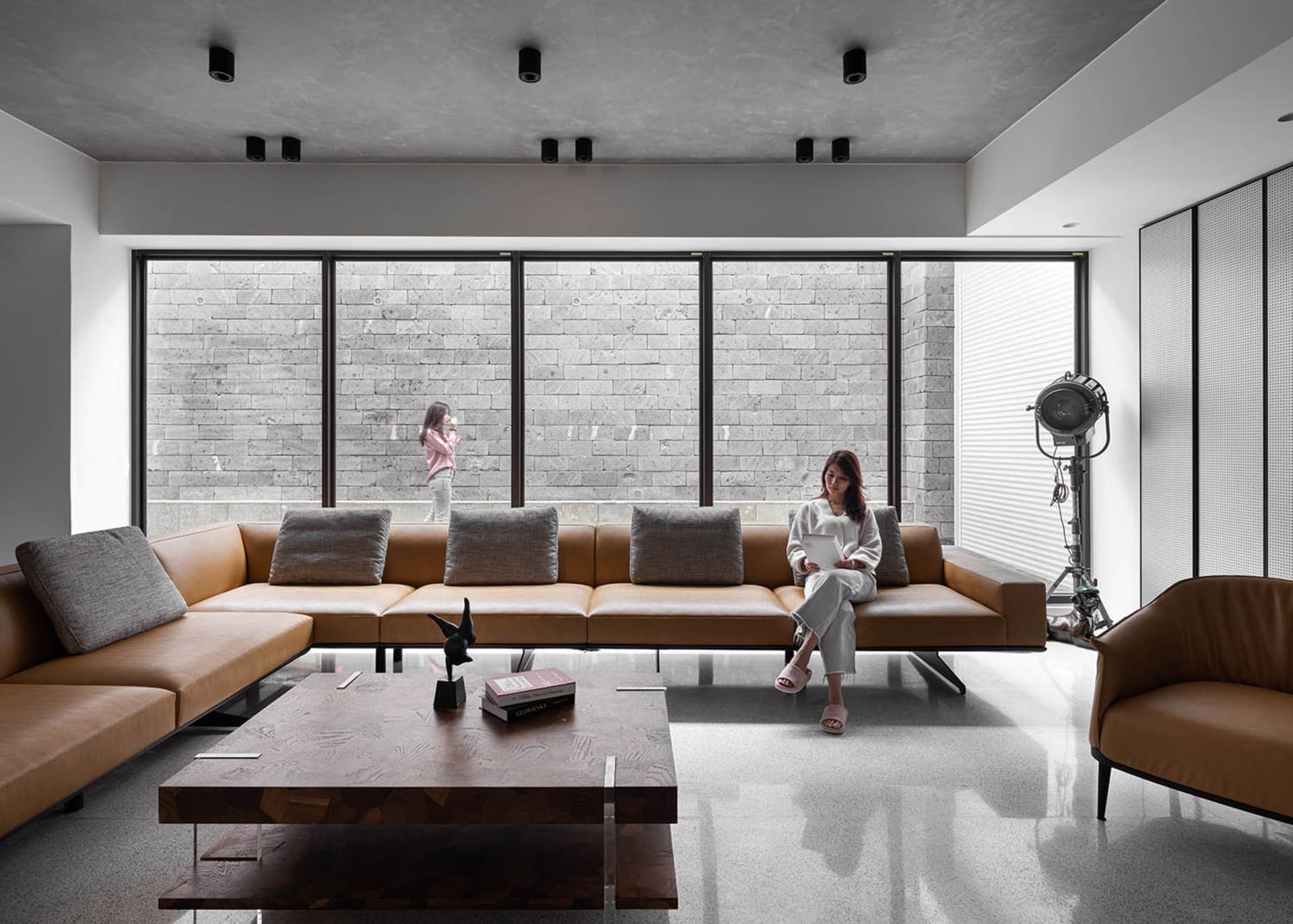 A modern living room with a leather sofa, wooden table, and stone wall.