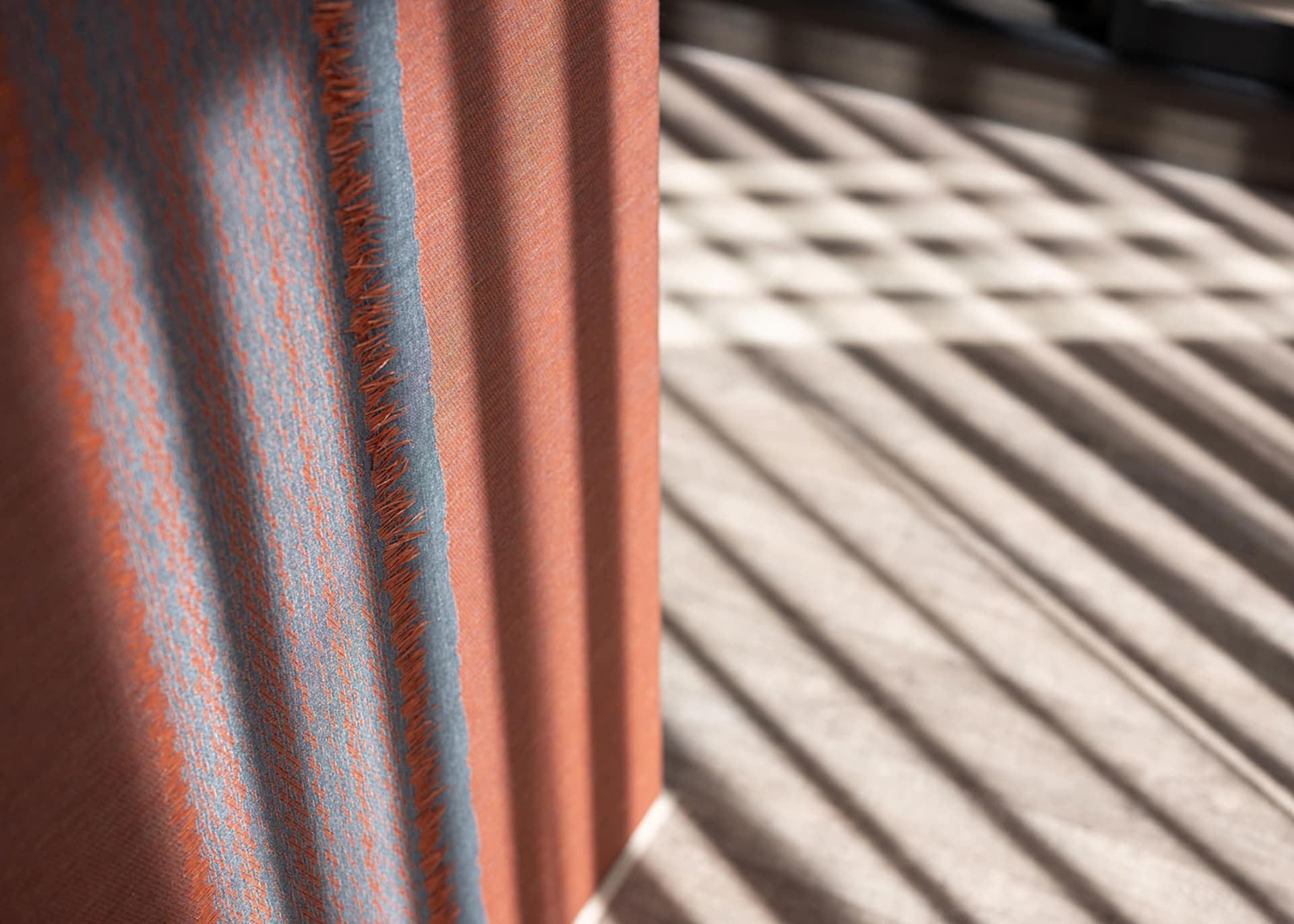A close-up view of a fabric with an orange and gray textured floor pattern.