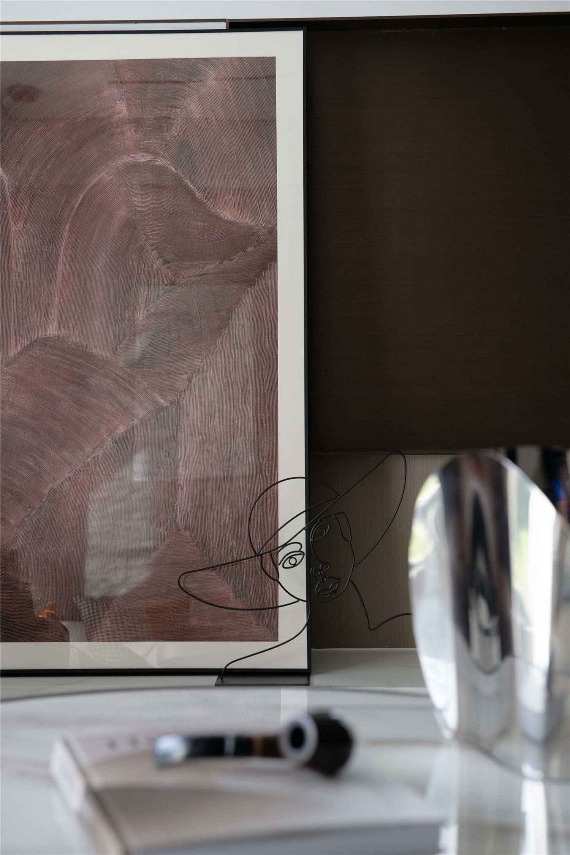 A wire sculpture of a woman's face on a coffee table in a modern interior setting.