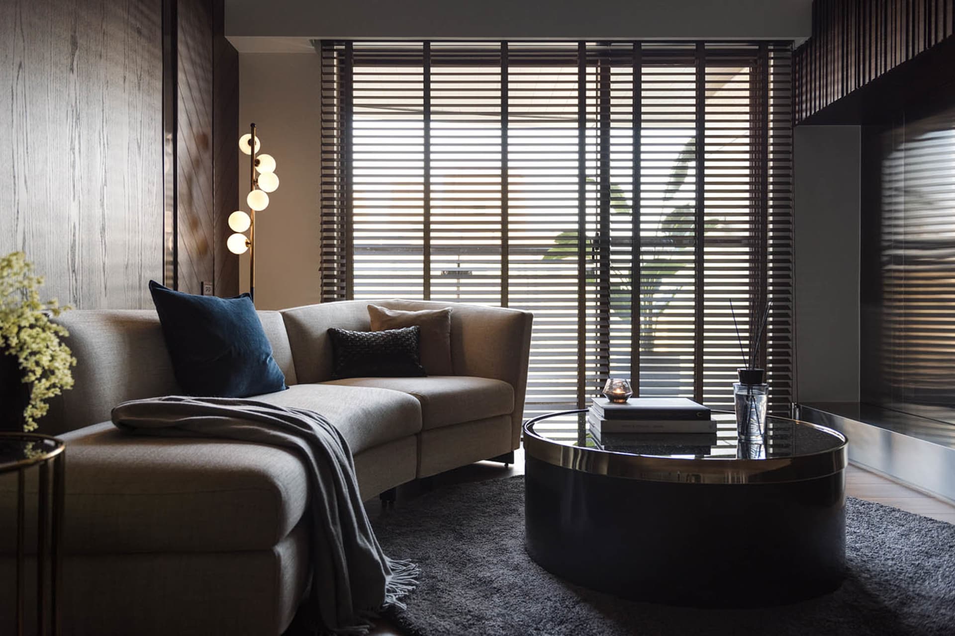 A modern living room featuring a beige sectional sofa with textured fabric and a concrete finish, positioned in front of a la