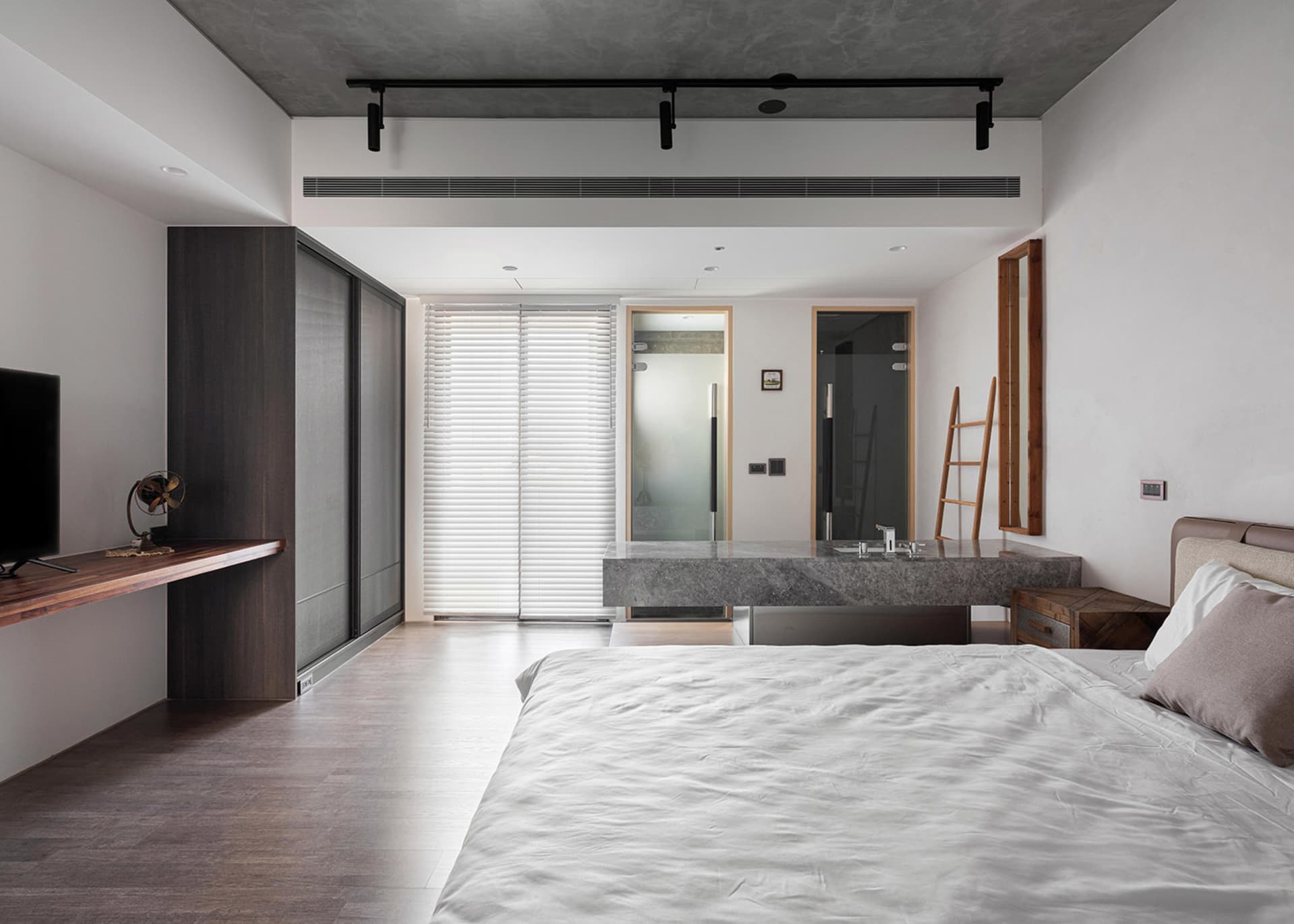 Modern minimalist bedroom with concrete, wood, and white bedding.