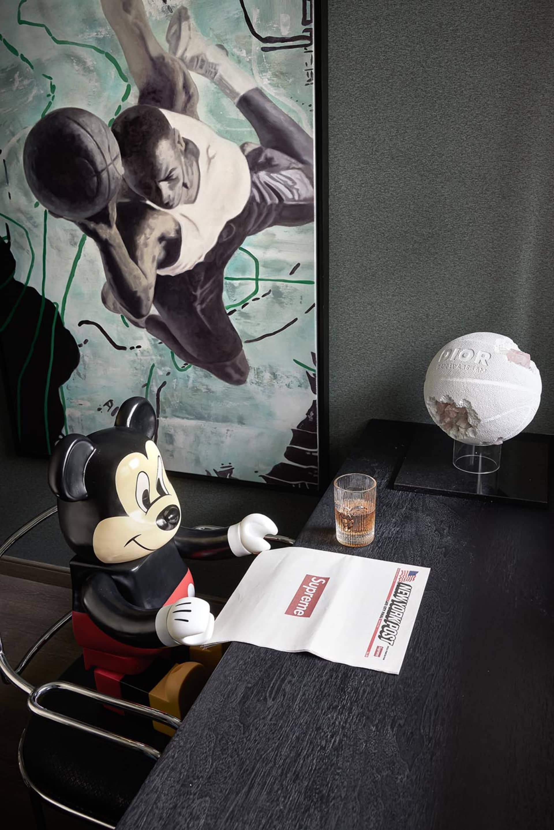 A modern minimalist interior featuring a black and white theme with a Mickey Mouse figurine holding a newspaper, a basketball
